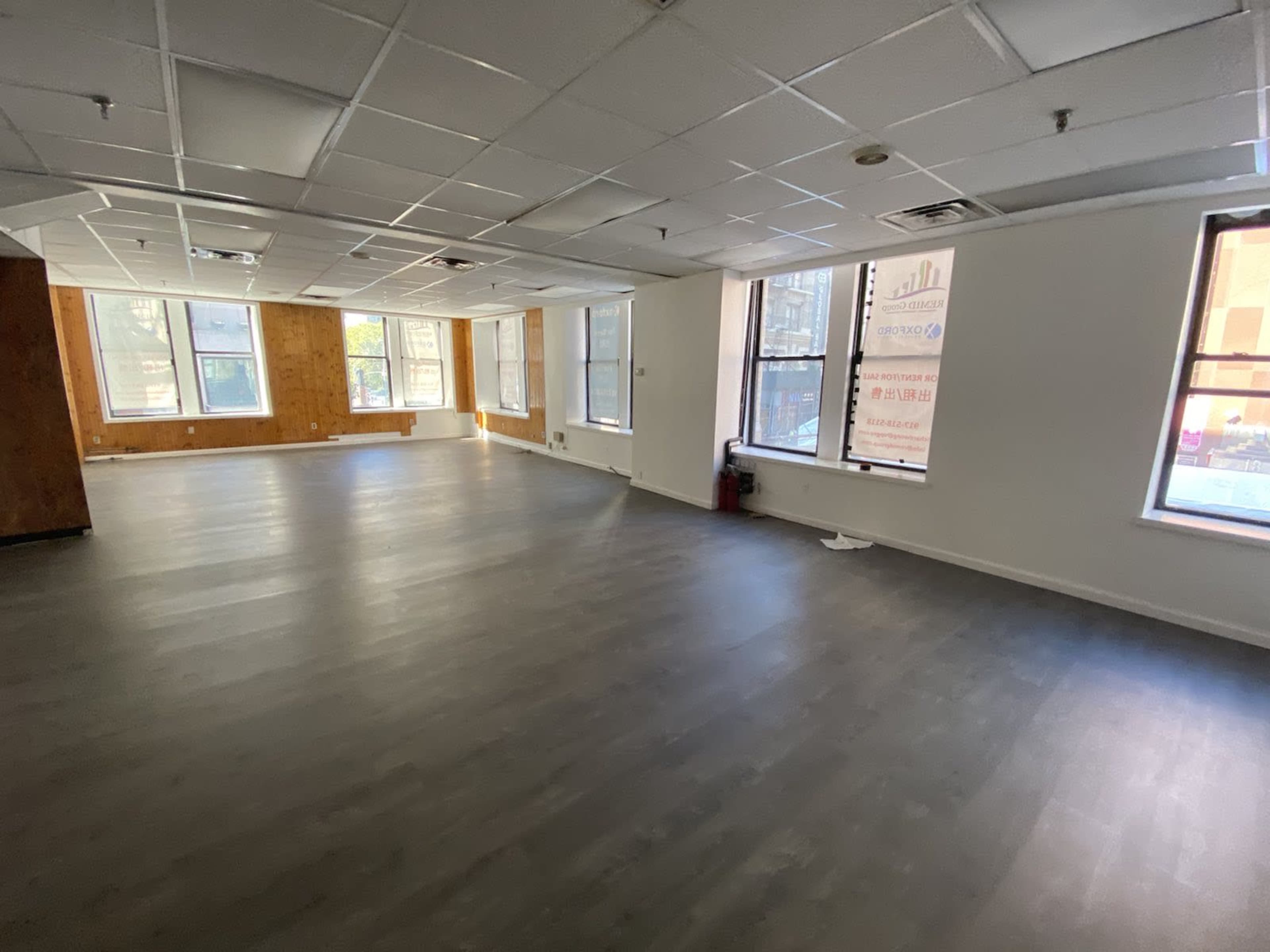 A spacious, empty room with large windows and a light-colored floor.