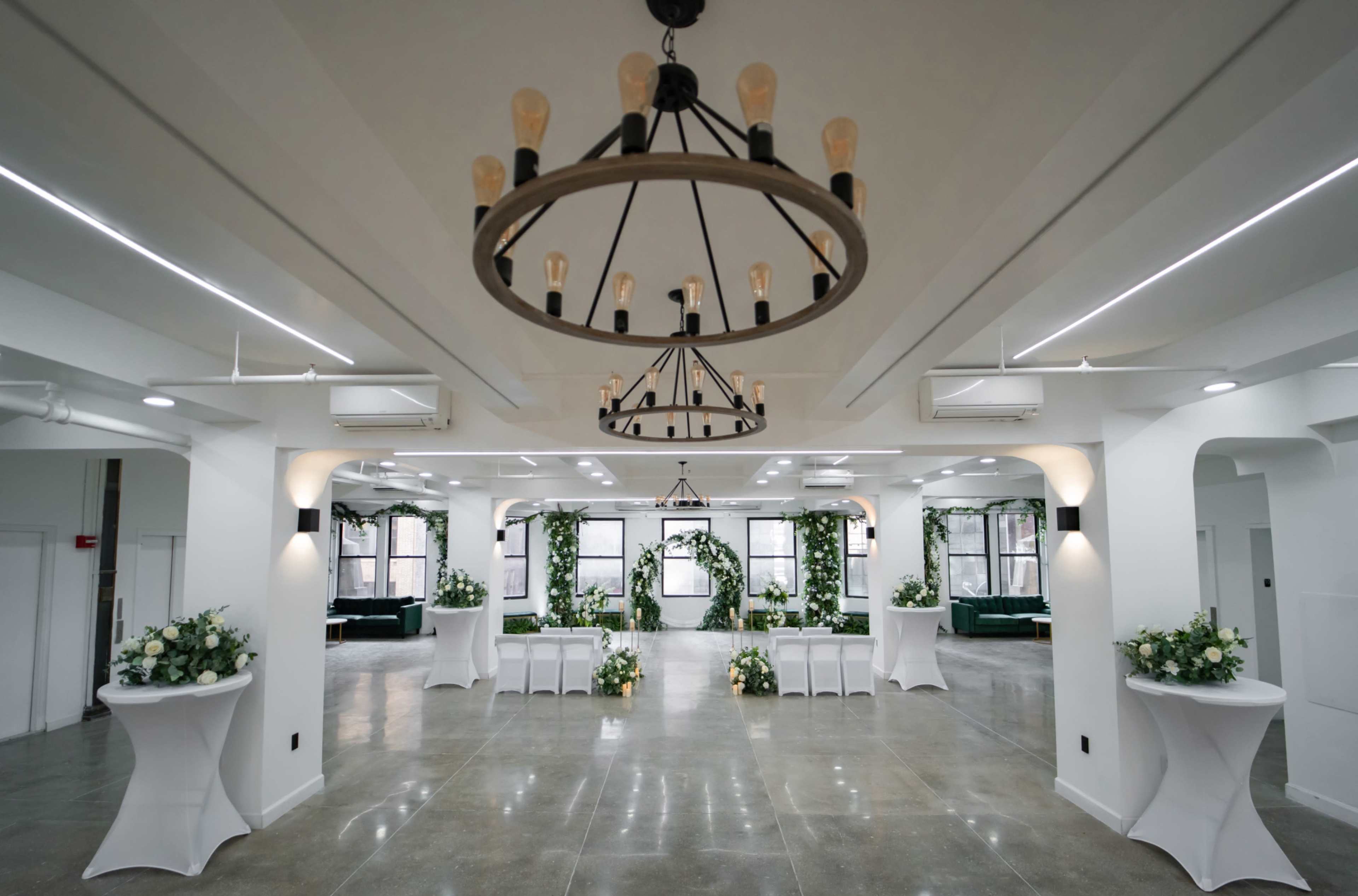 A spacious interior room features multiple seating arrangements, floral centerpieces, and decorative chandeliers.