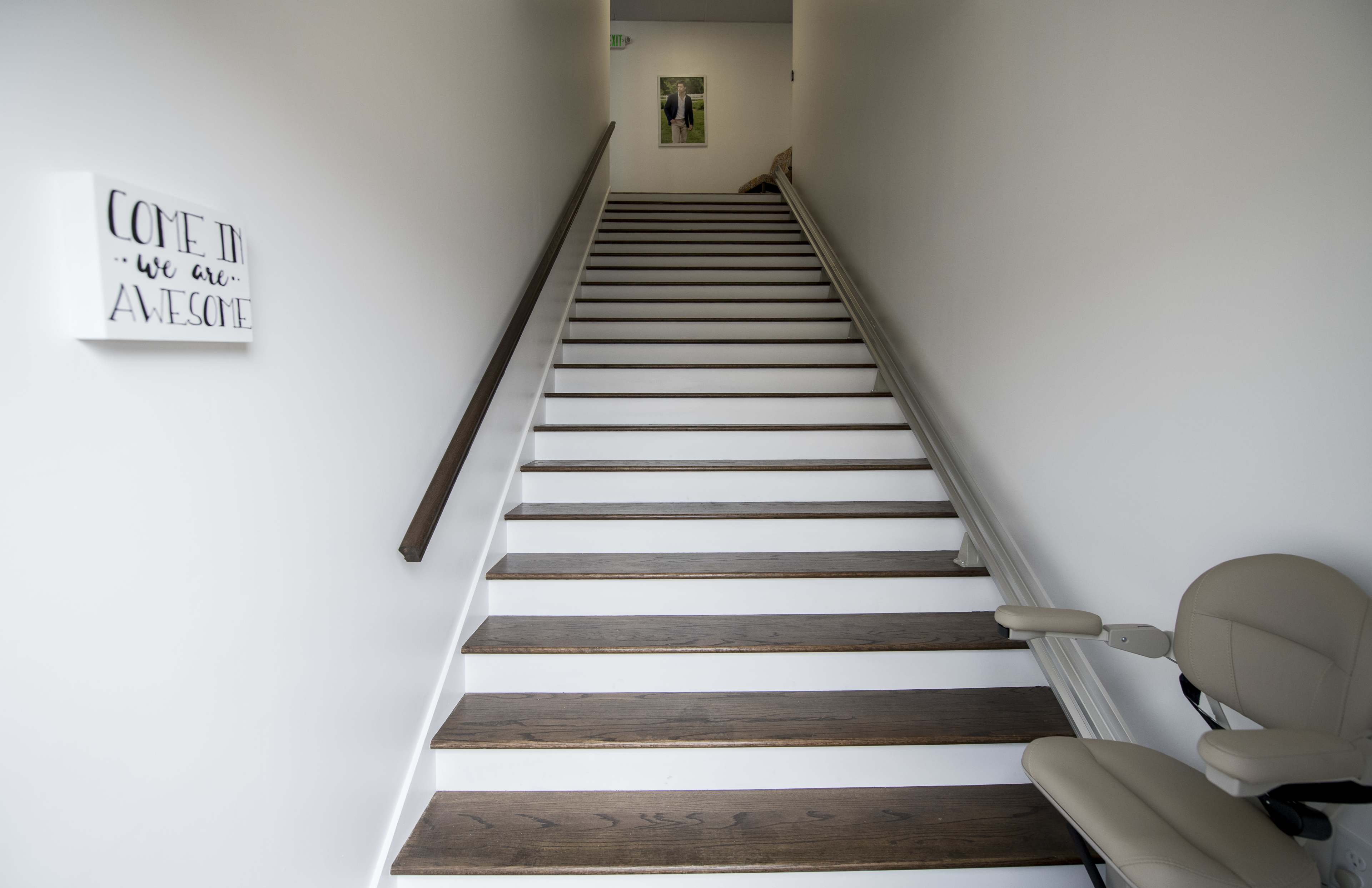 A staircase with wooden steps leads upwards, accompanied by a sign on the wall that reads "Come in, we are awesome."