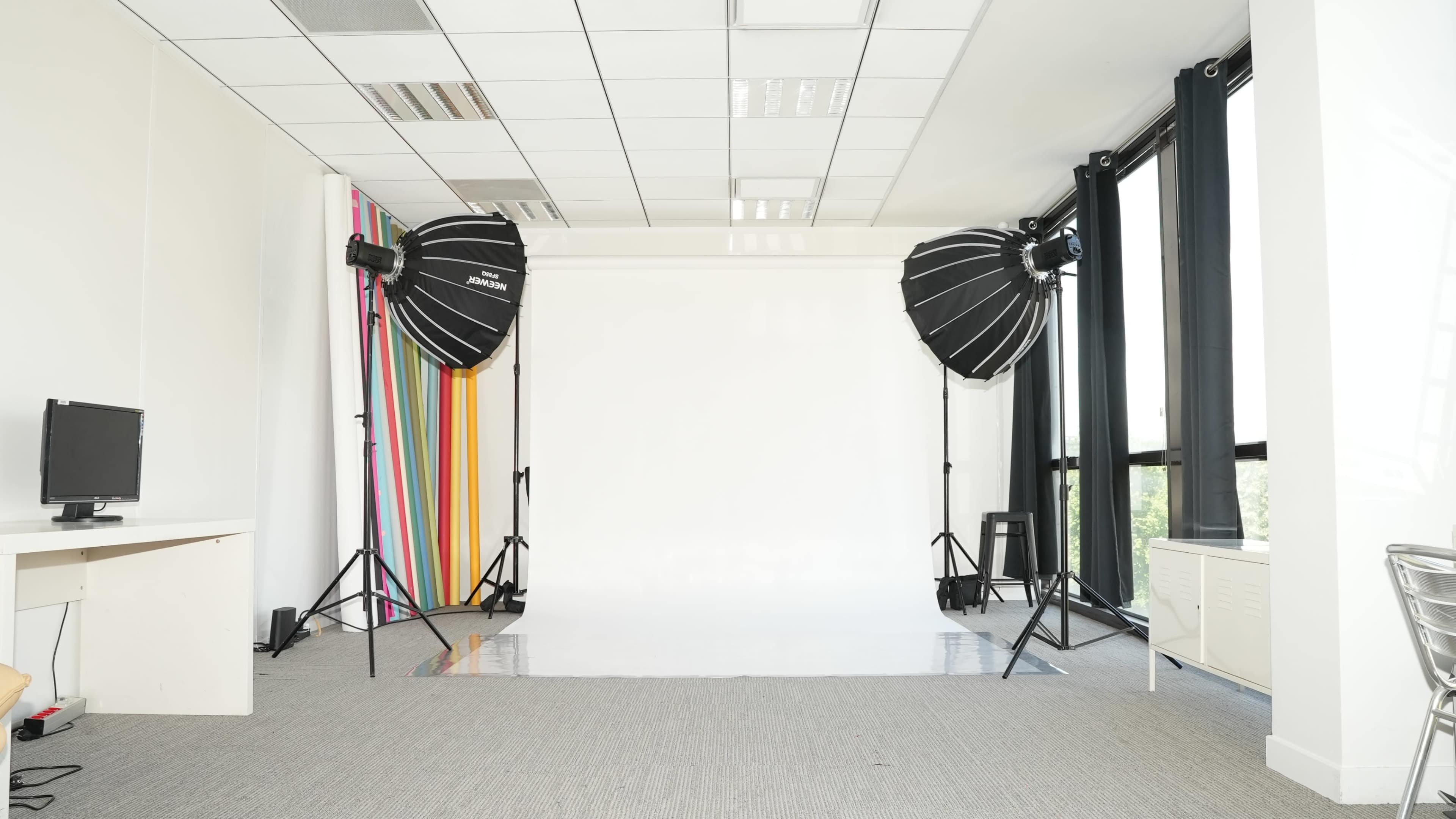 A photography studio features two large softbox lights and a empty backdrop against a wall with colorful stripes.