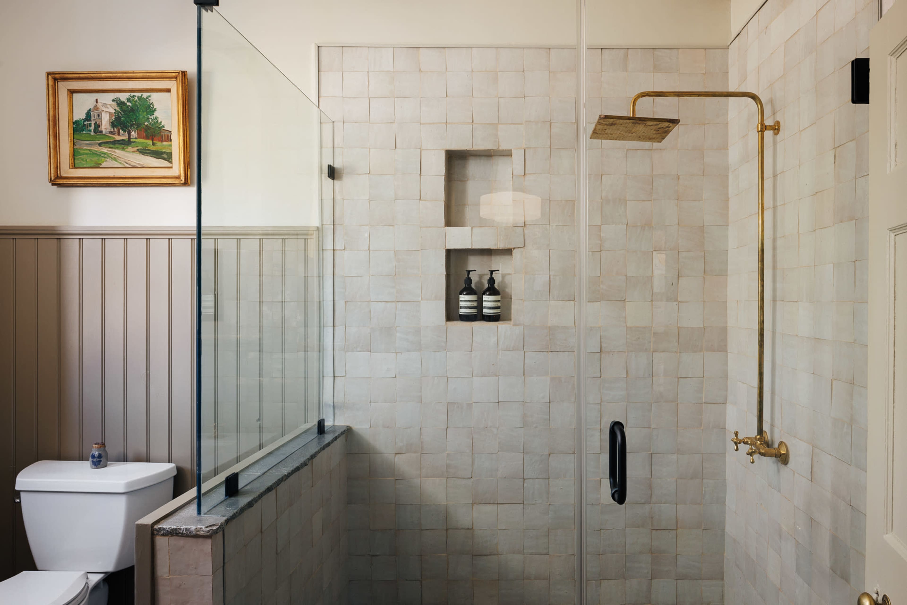 A modern bathroom featuring a glass-enclosed shower with light-colored tiled walls and a minimalist design.