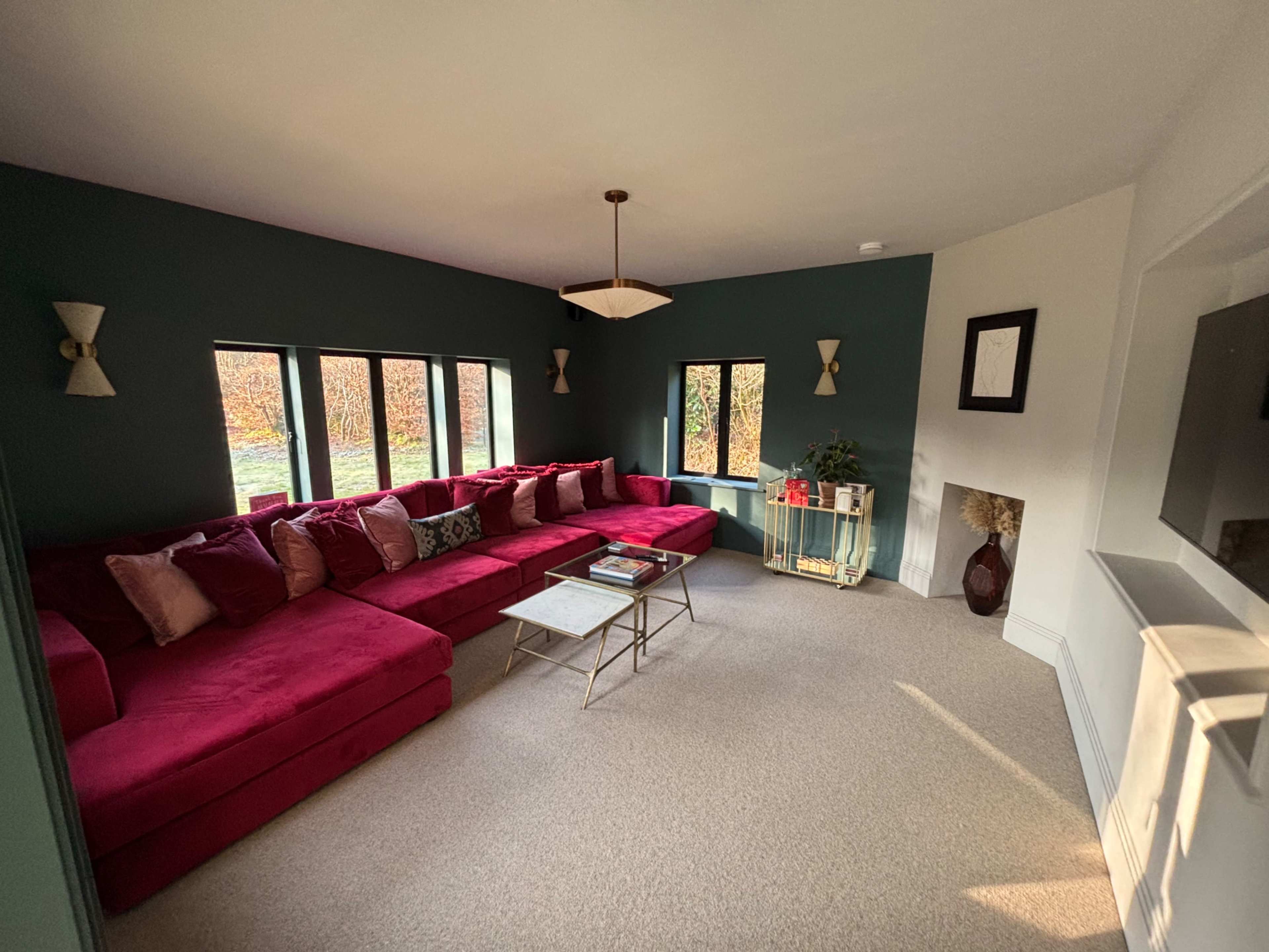 The living room features a large red sectional sofa, a coffee table, and windows that provide natural light.