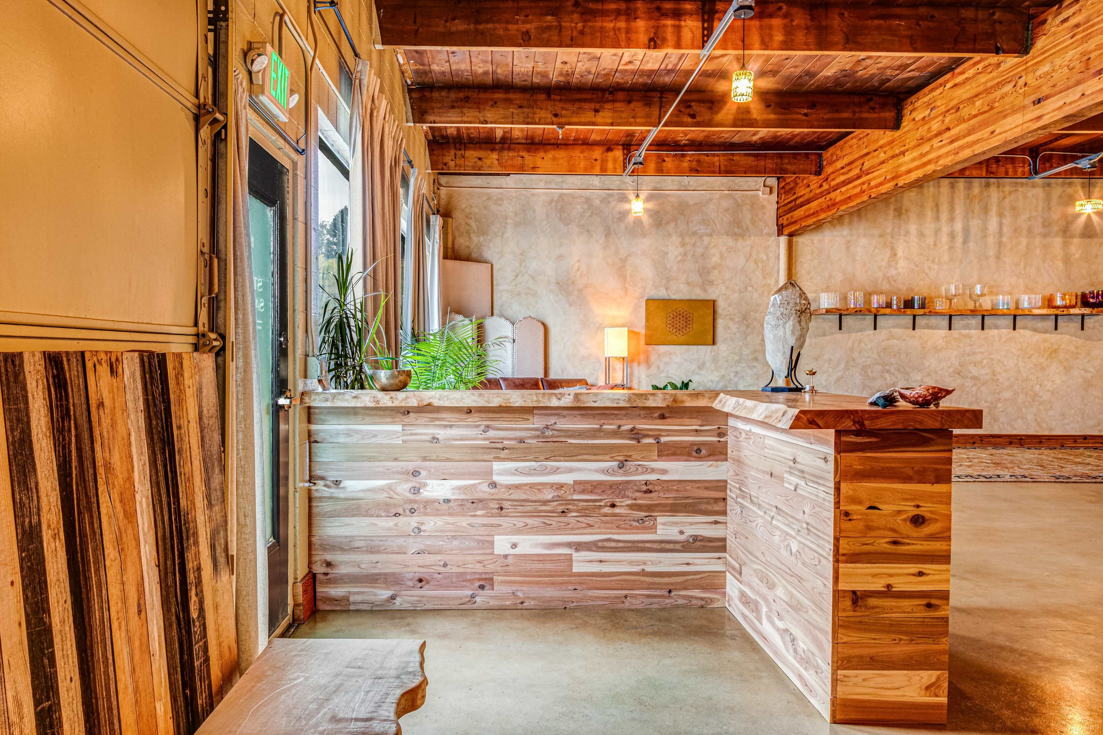 The image shows a wooden reception area with a counter and decorative elements, featuring natural materials and warm lighting.