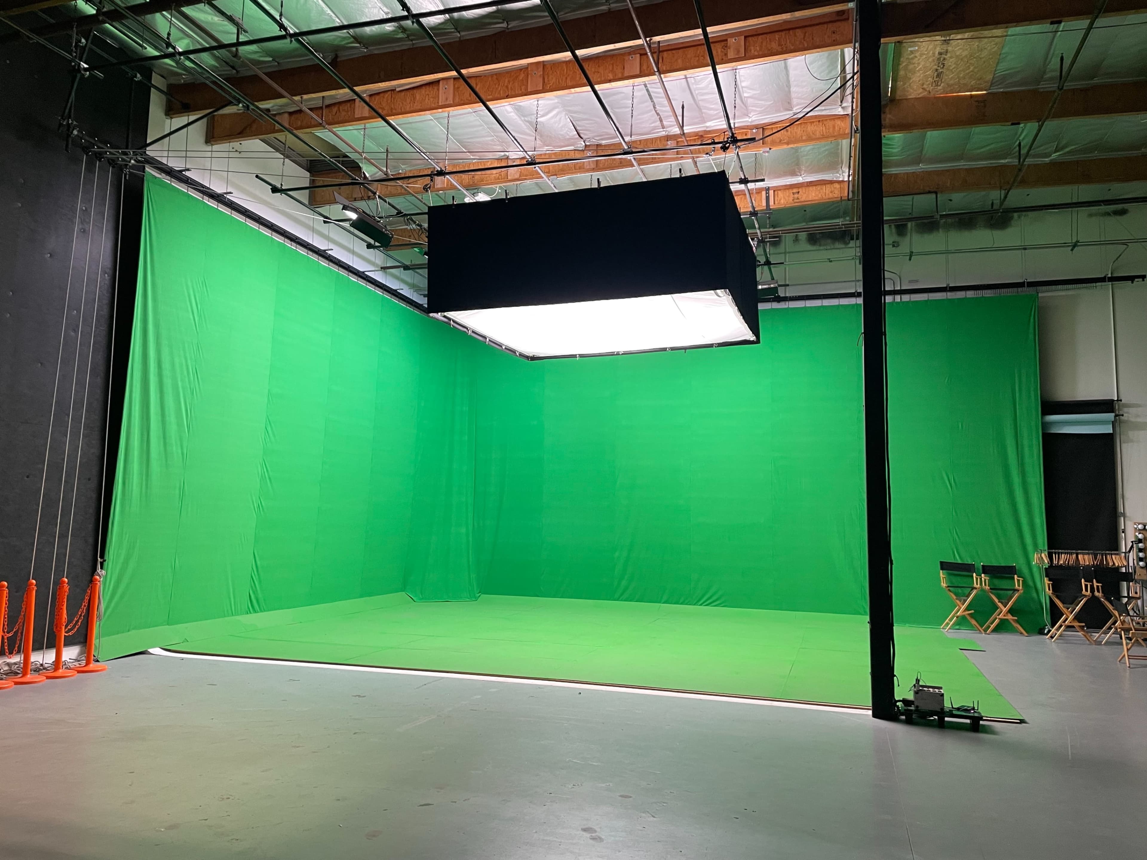 A green screen studio with a large green backdrop and a suspended light source in the center.
