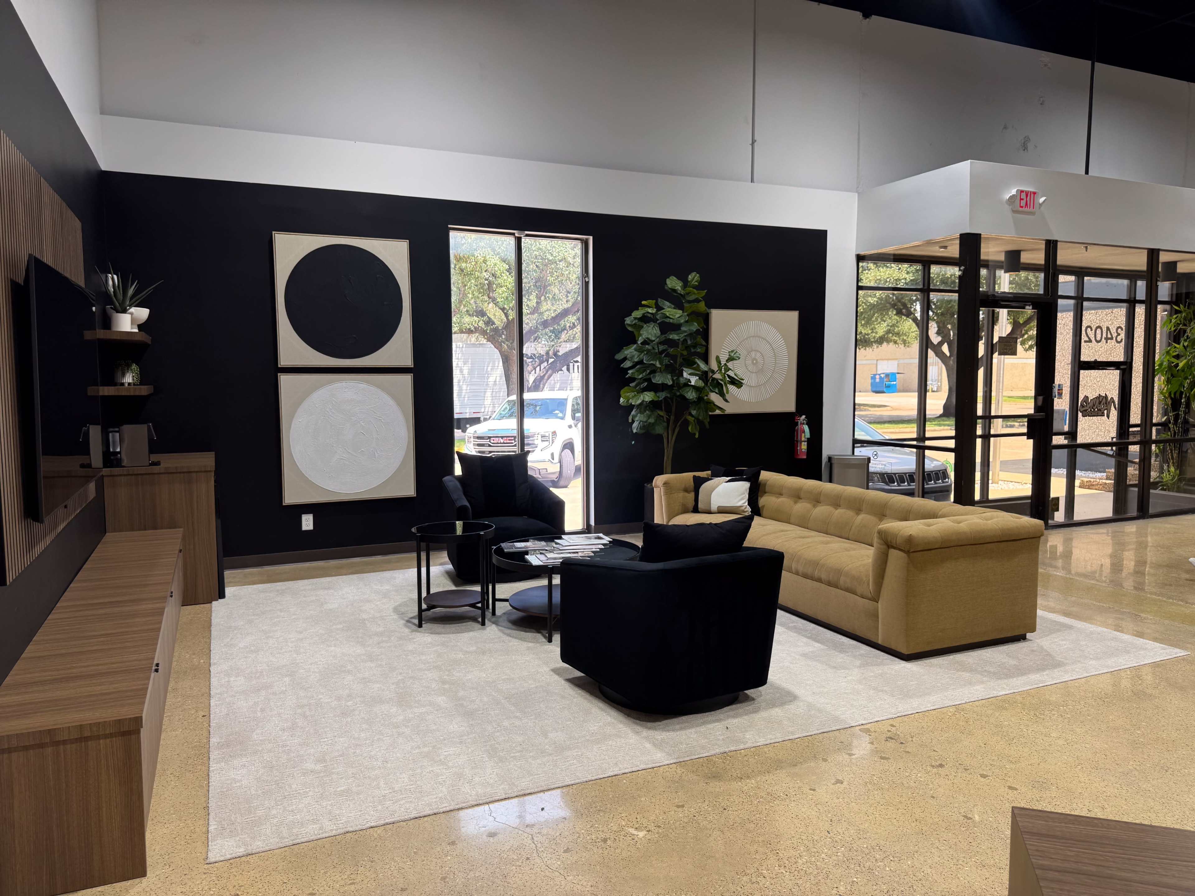The image shows a modern interior design of a living area featuring a yellow sofa, black chairs, a coffee table, and abstract wall art.