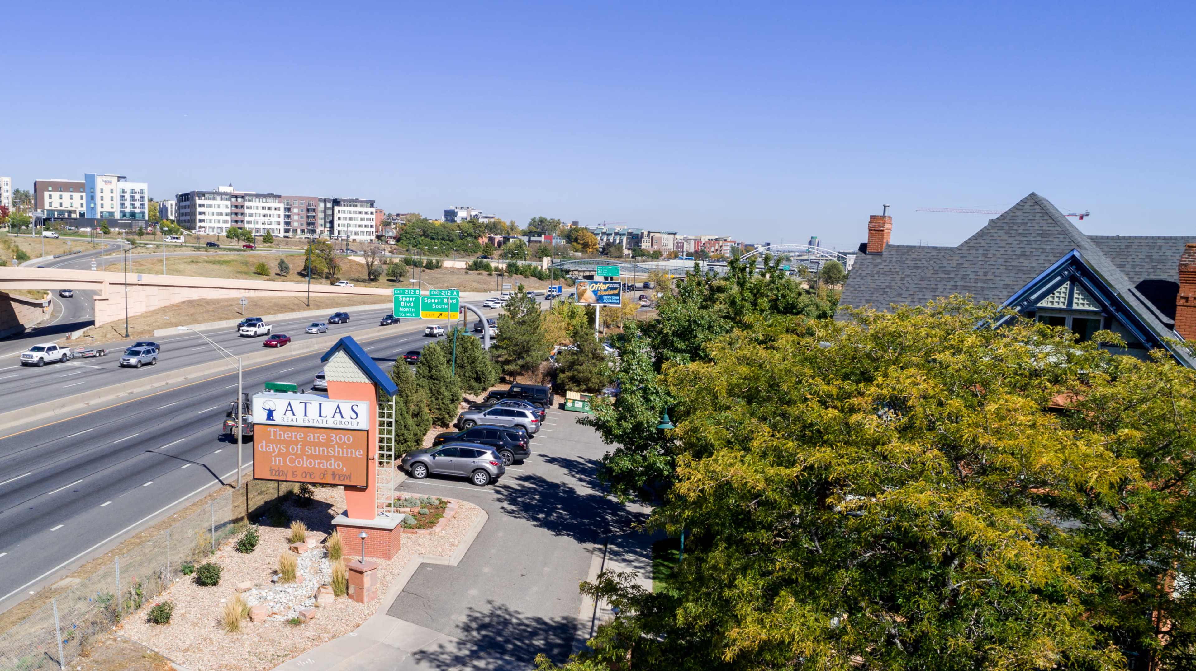 A highway with vehicles traveling alongside a sign for "Atlas" and a residential area in the foreground.