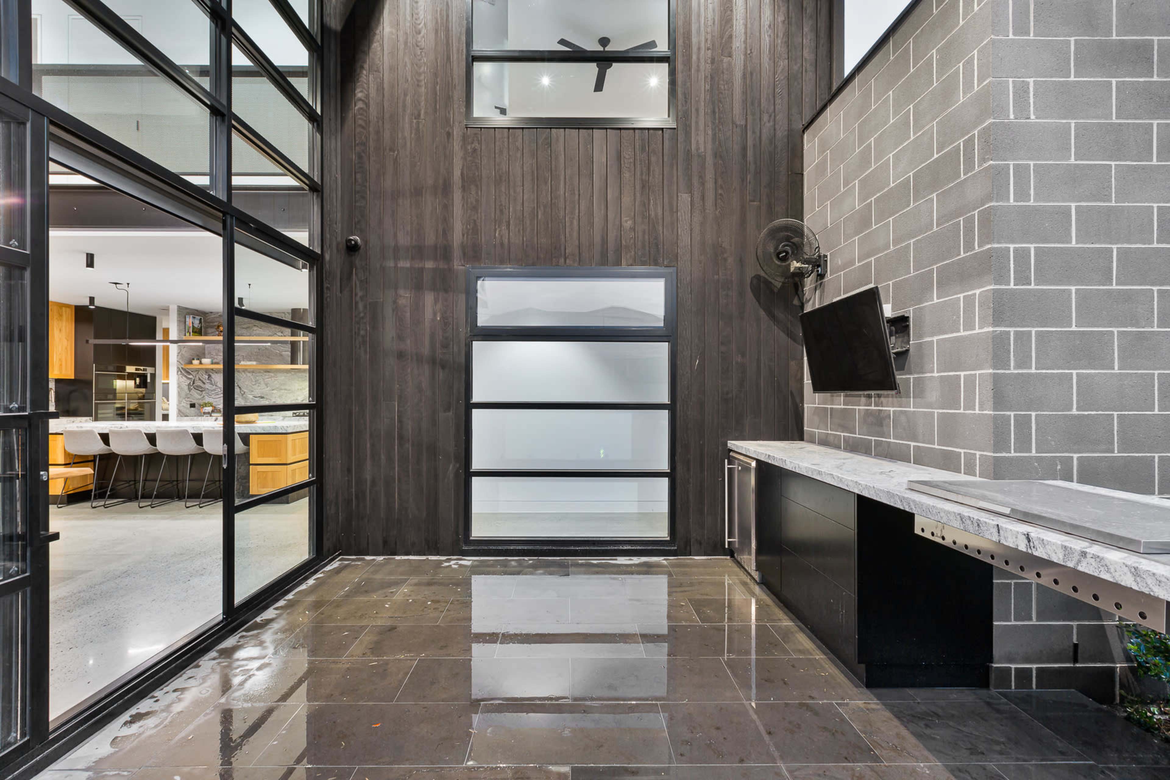 A modern outdoor patio with large glass doors, a stone countertop, and a wall made of gray bricks.
