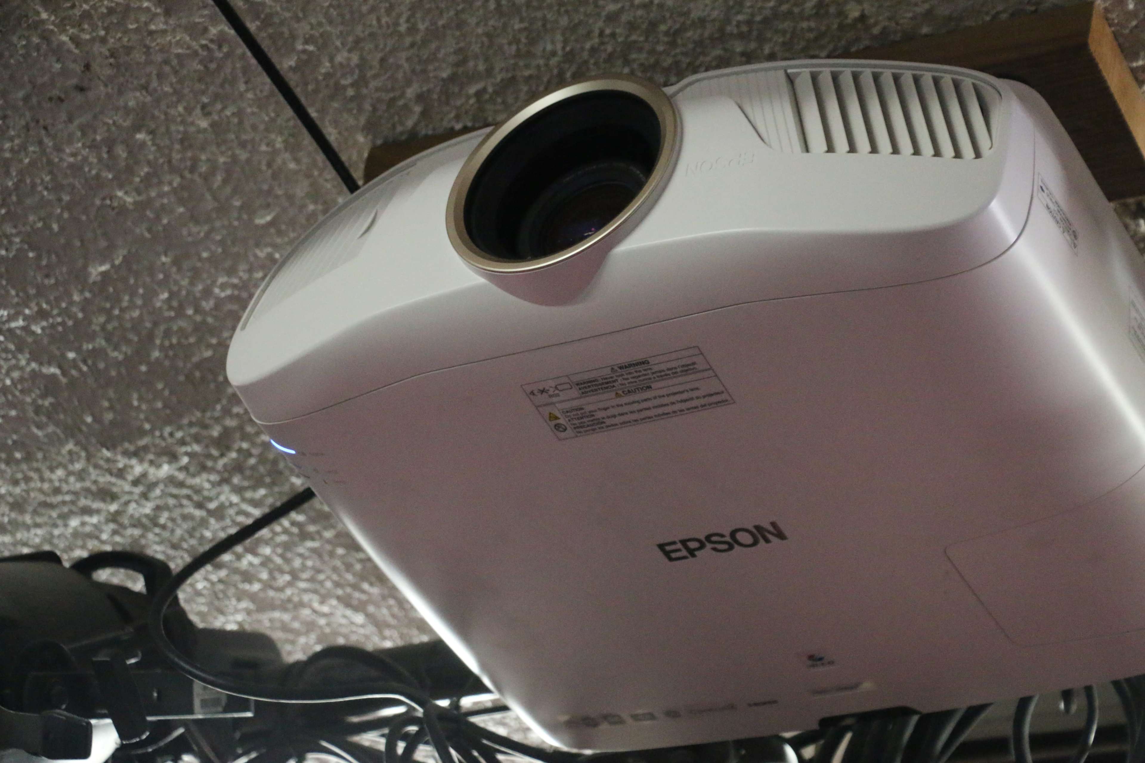 The image shows a white Epson projector mounted on a ceiling.