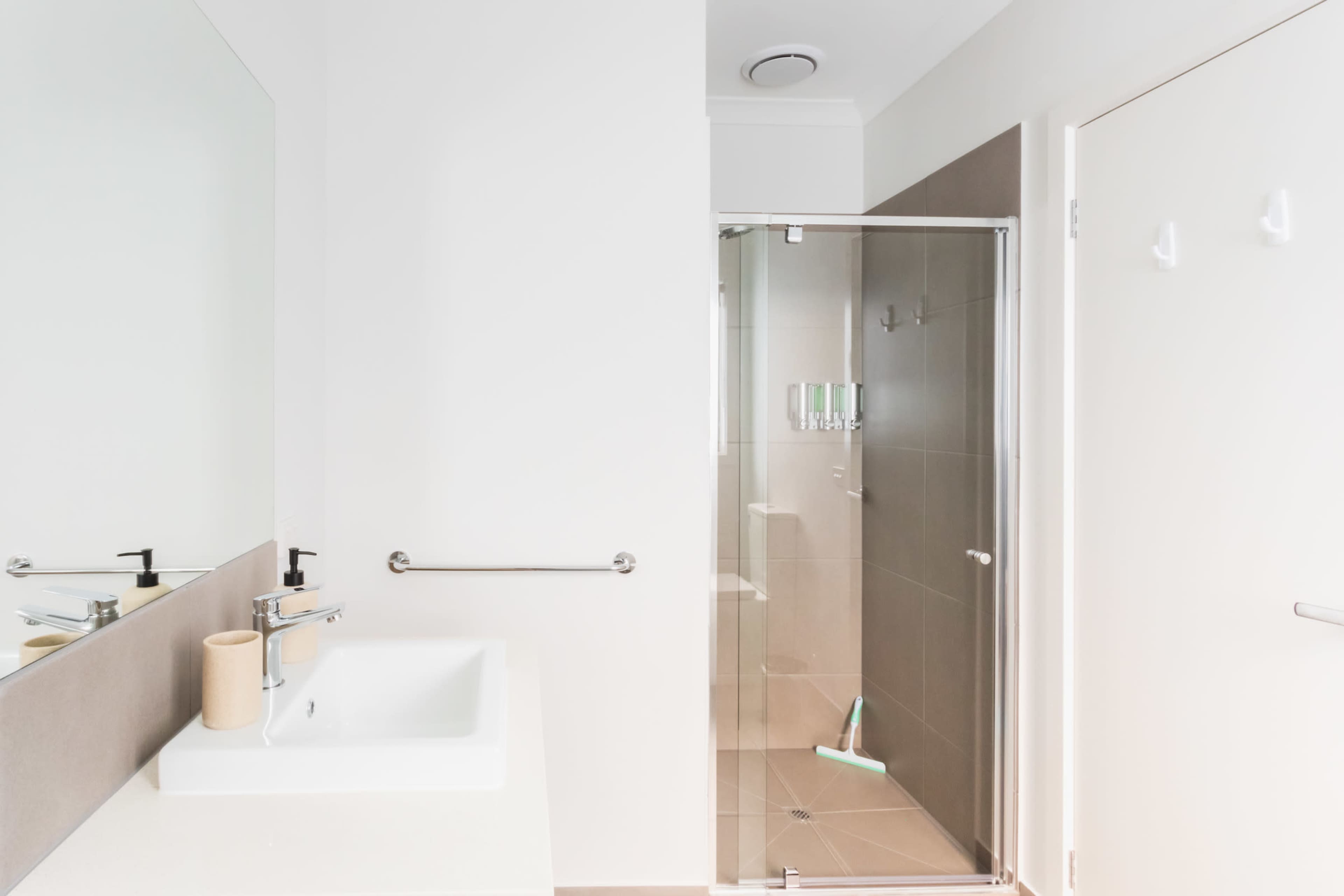 A modern bathroom features a glass-enclosed shower, a minimalist sink, and a large wall mirror.