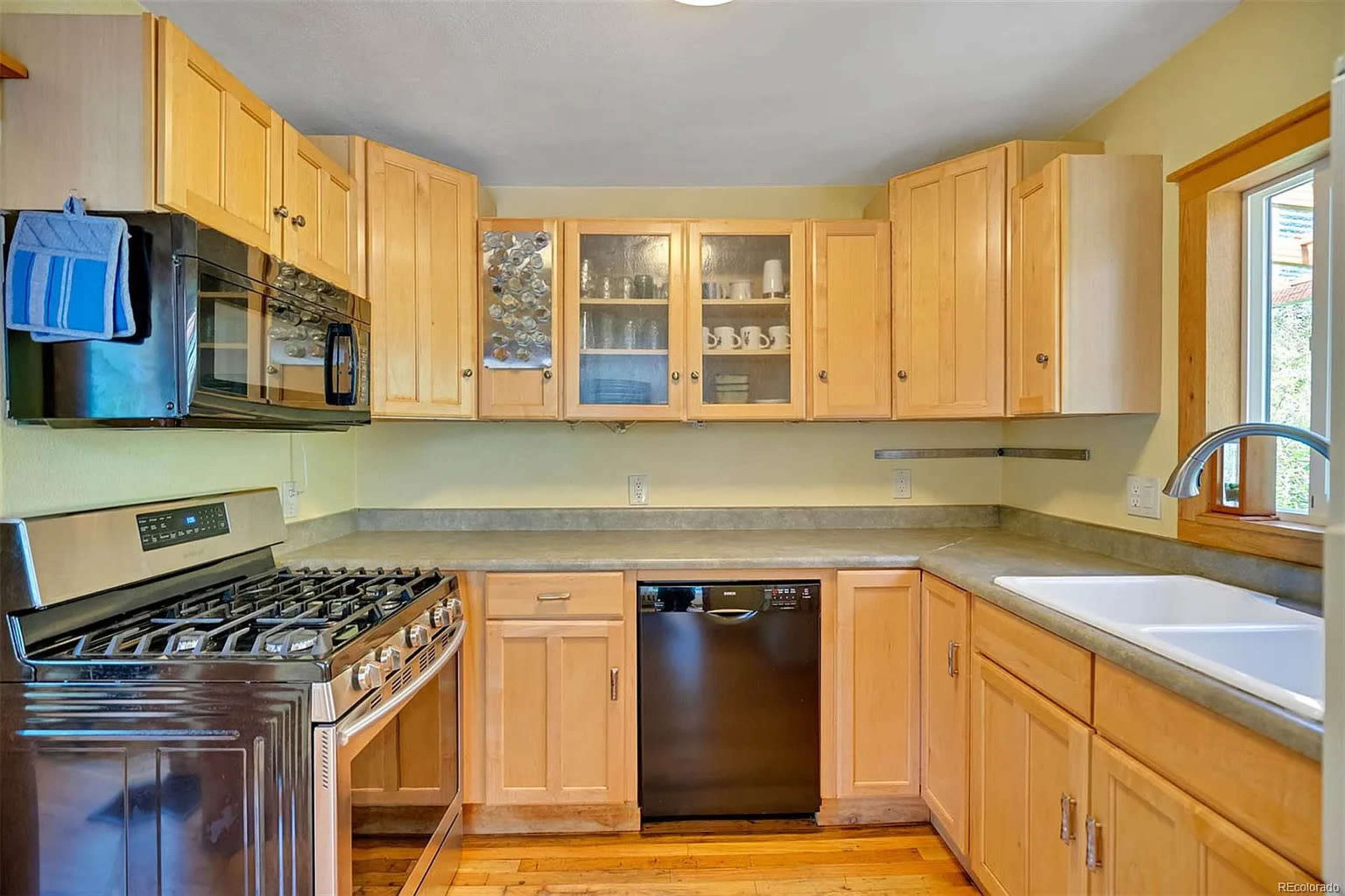 The kitchen features wooden cabinets, stainless steel appliances, and a double sink with a countertop.