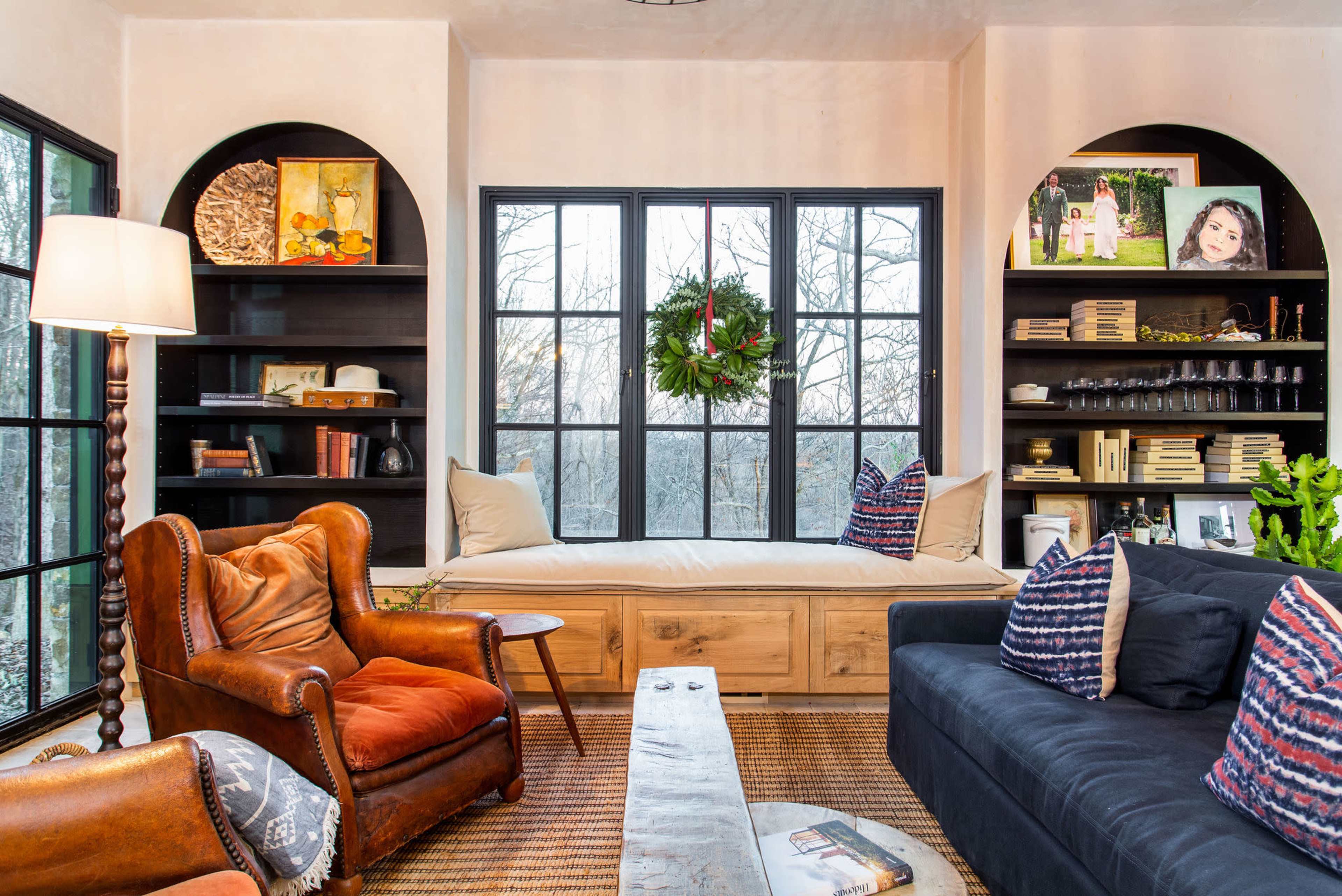 A cozy living room with a window seat, built-in bookshelves, and a mix of seating arrangements, including a classic armchair and a modern sofa.