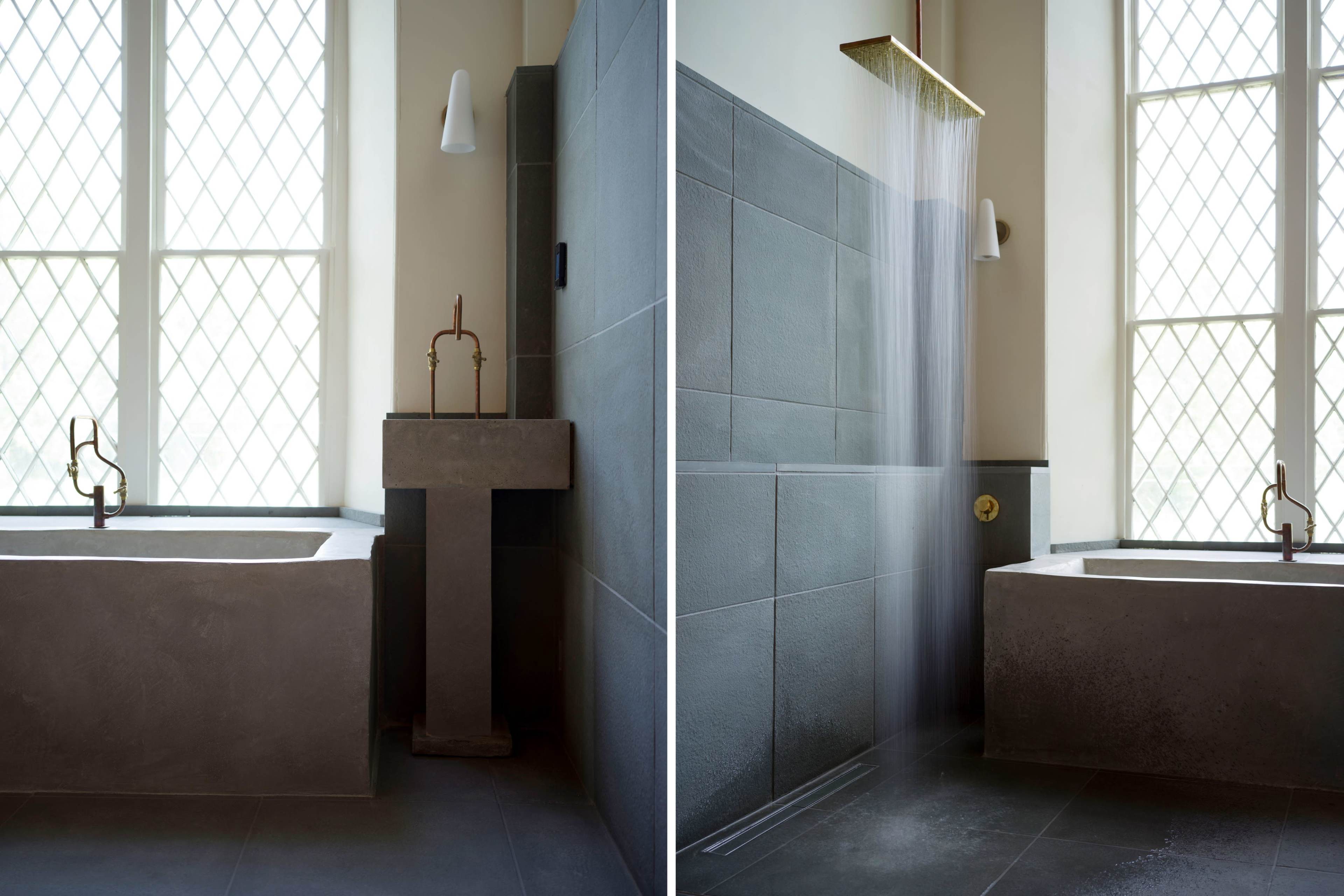 A modern bathroom with a freestanding tub, a minimalist sink, and a wall-mounted shower, illuminated by natural light through large windows.