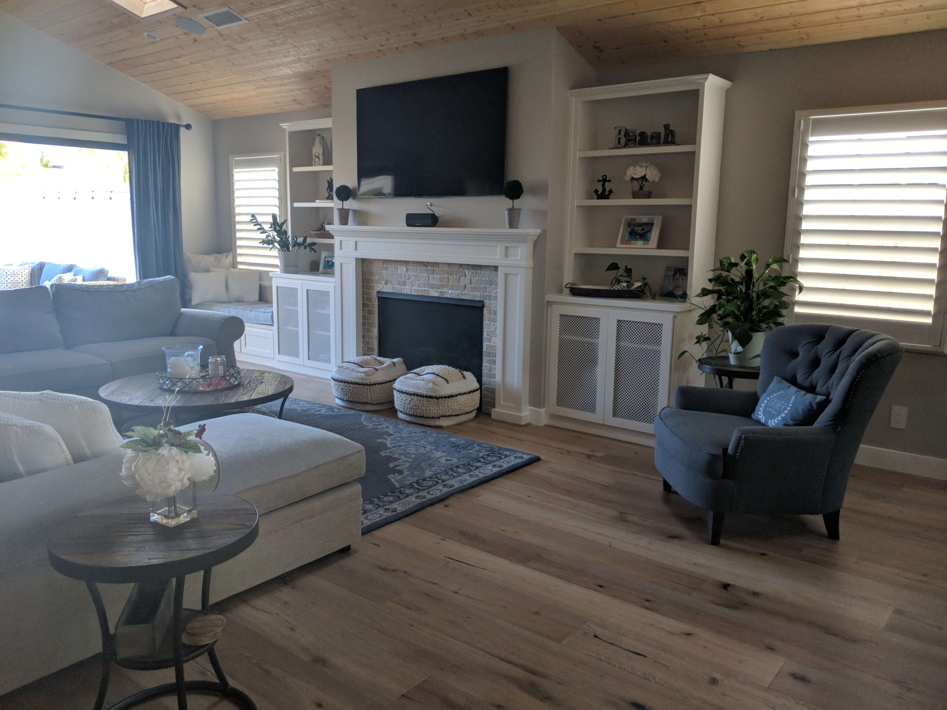 A modern living room featuring a sectional sofa, a coffee table, a large television above a fireplace, and built-in shelves filled with decorative items.
