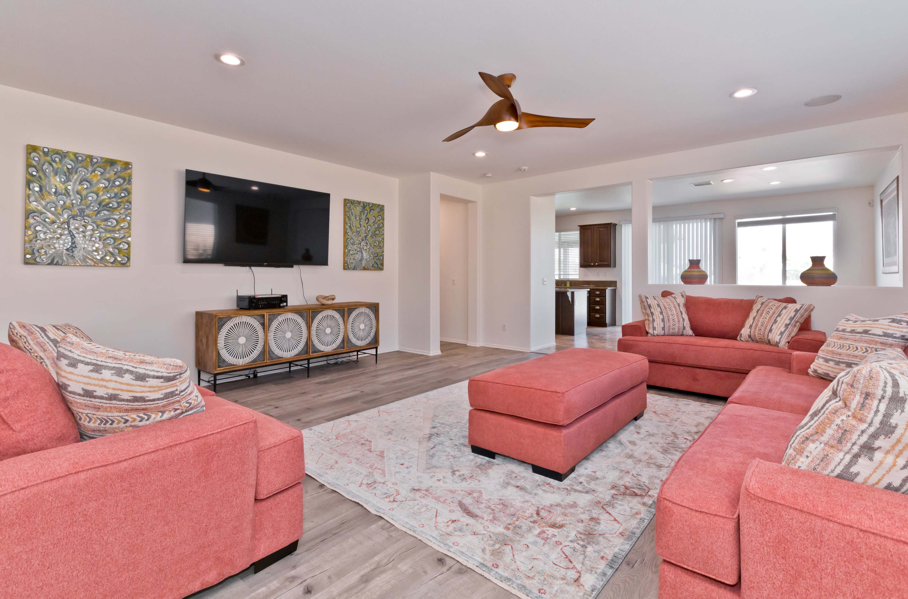 A modern living room with coral-colored seating, a large area rug, and decorative wall art.