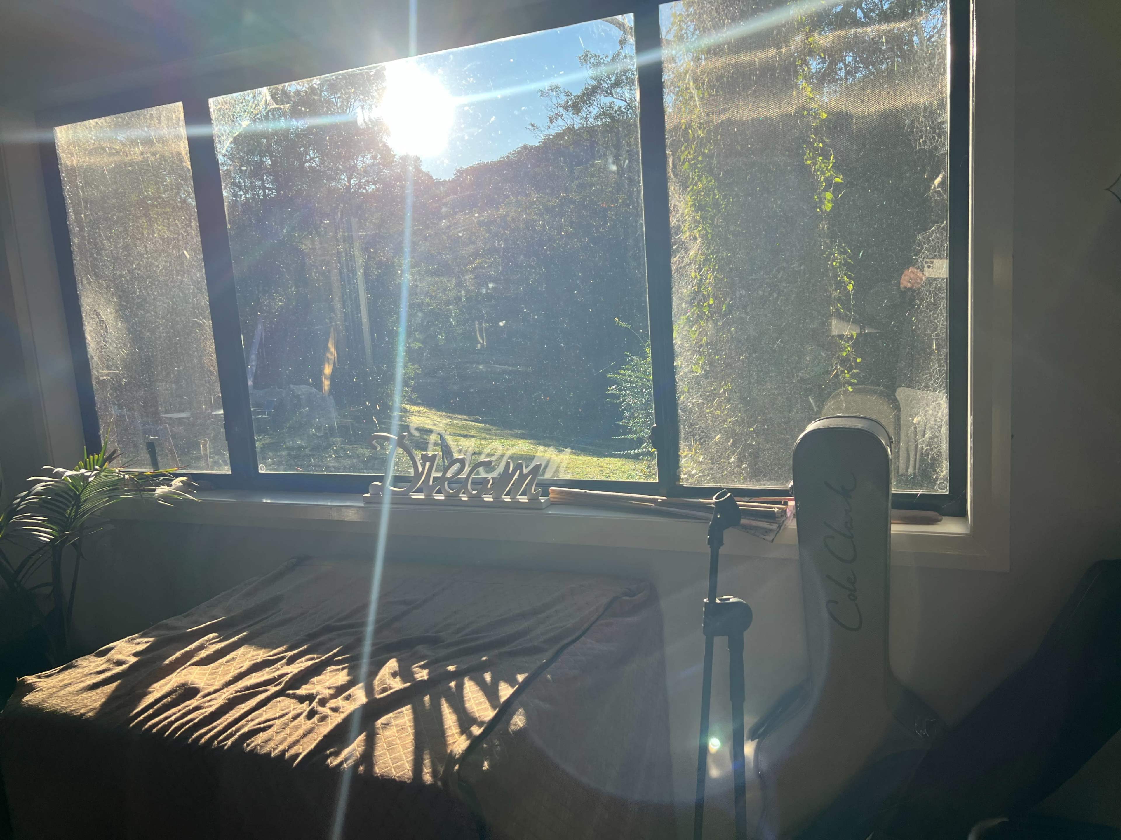 Sunlight streams through a large window, illuminating a room with a table and a chair beside a garden view.