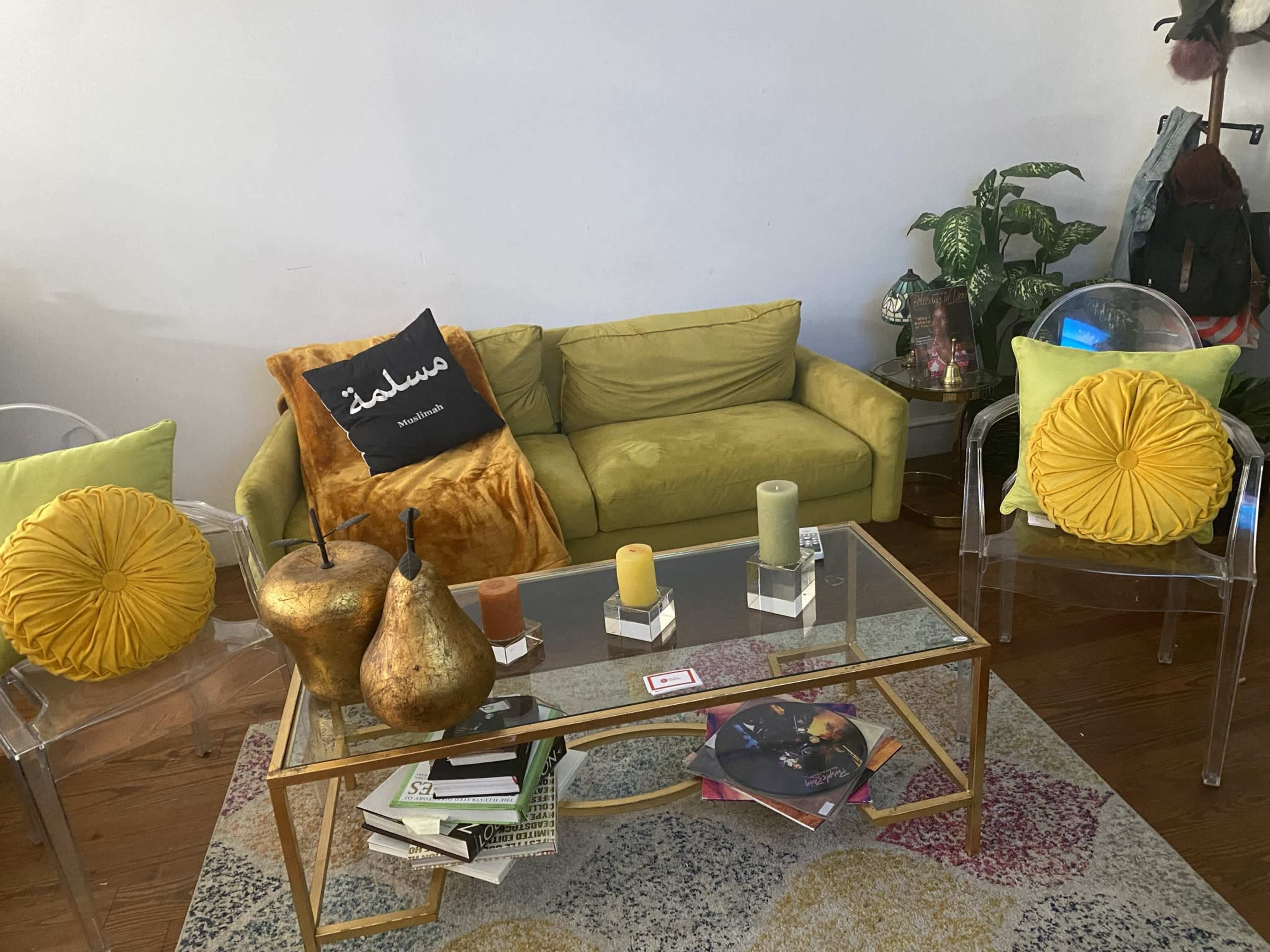 A living room with a bright green sofa, yellow accent pillows, a glass coffee table with decorative items, and indoor plants.