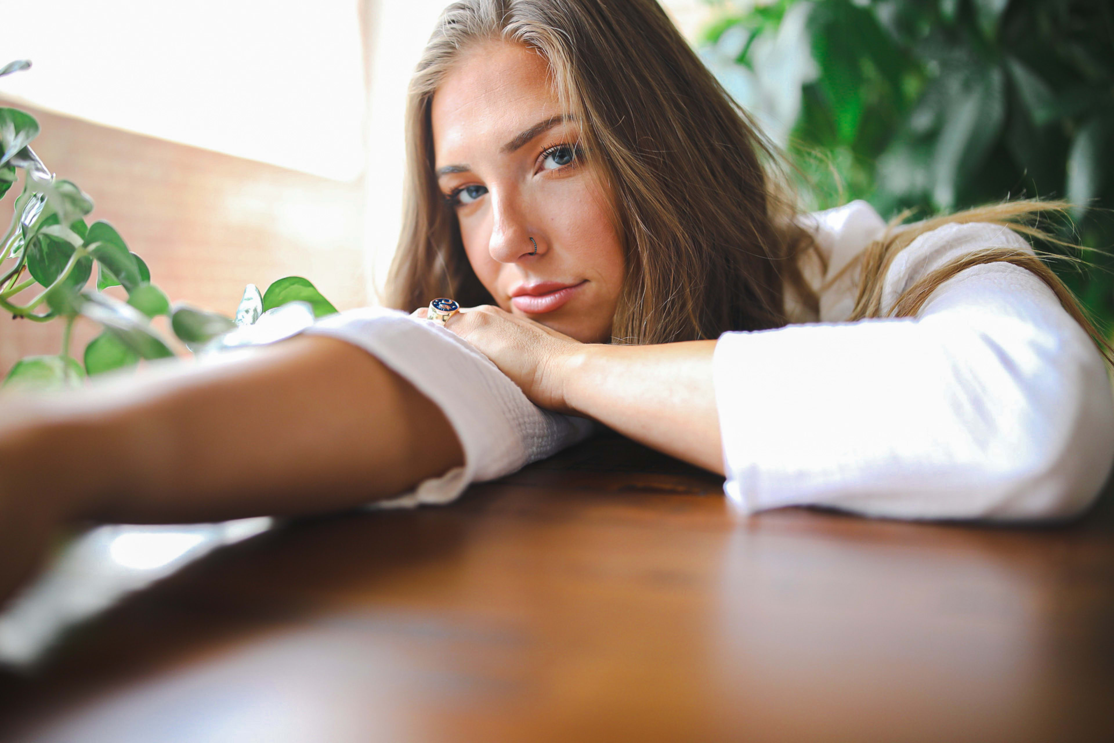 Un portrait d'une femme assise à une table avec une plante verte autour d'elle.