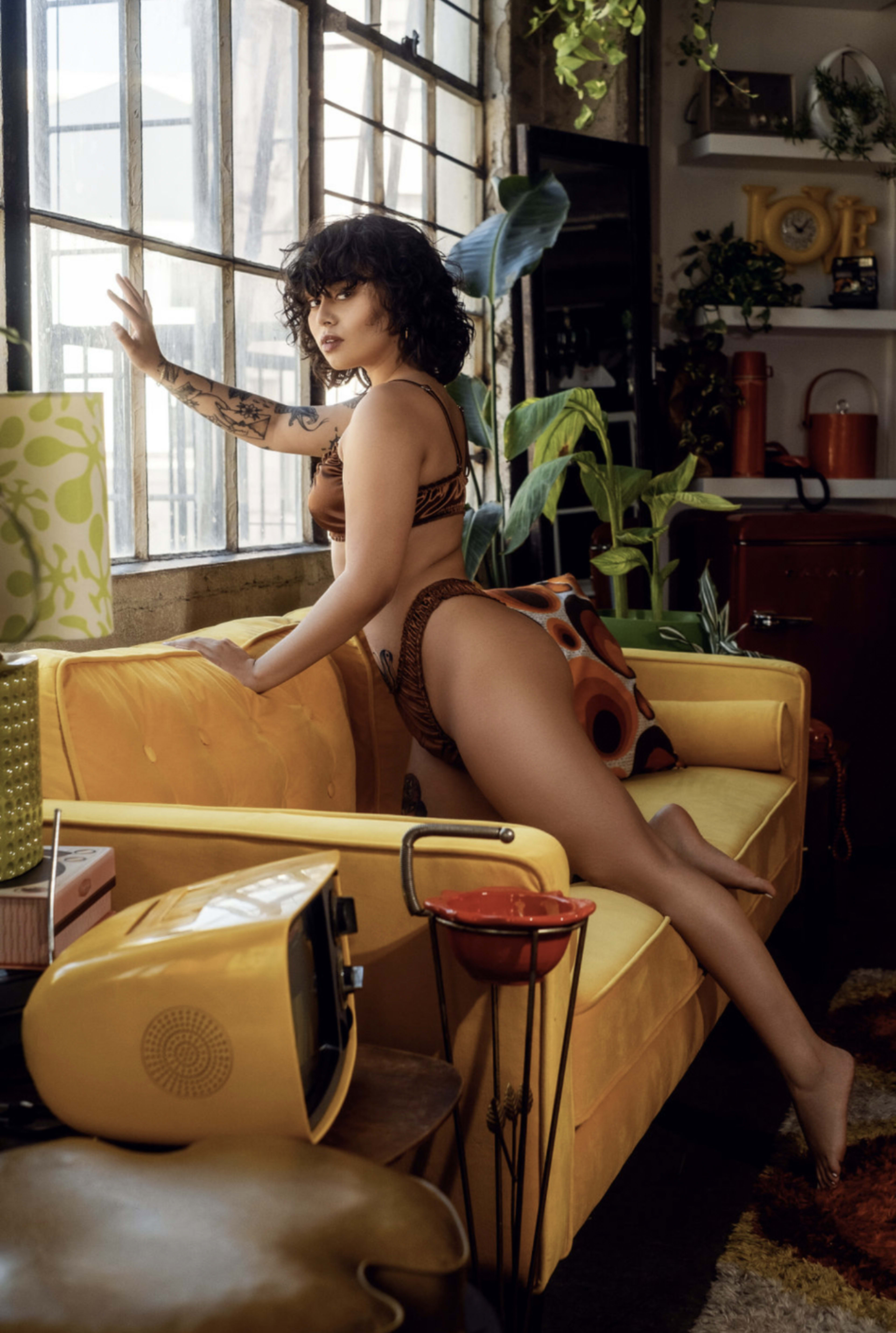 A woman posing on a yellow couch.