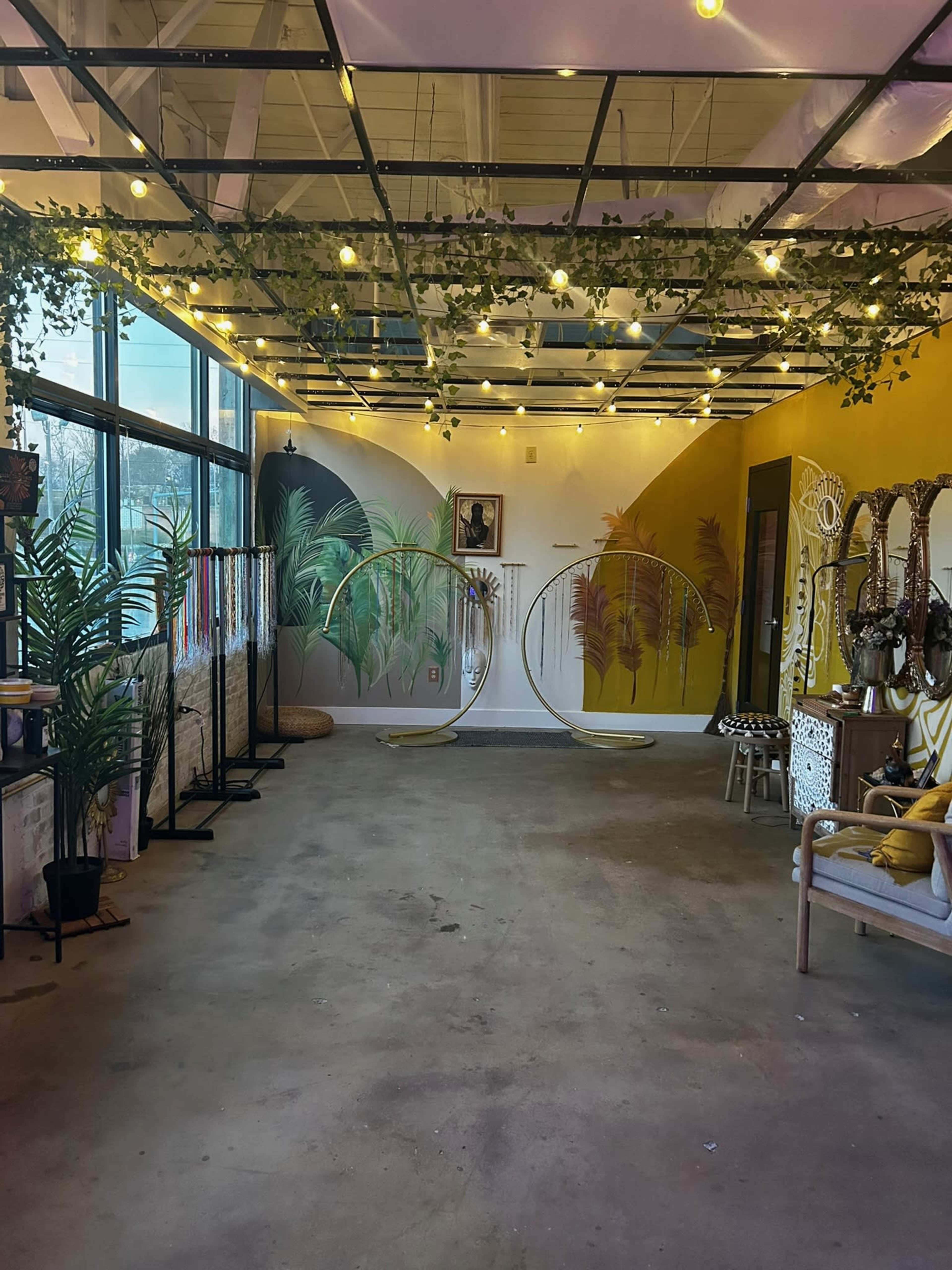 The image shows an indoor space featuring two large circular frames, a colorful mural on the wall, and various decorative elements including plants and string lights.