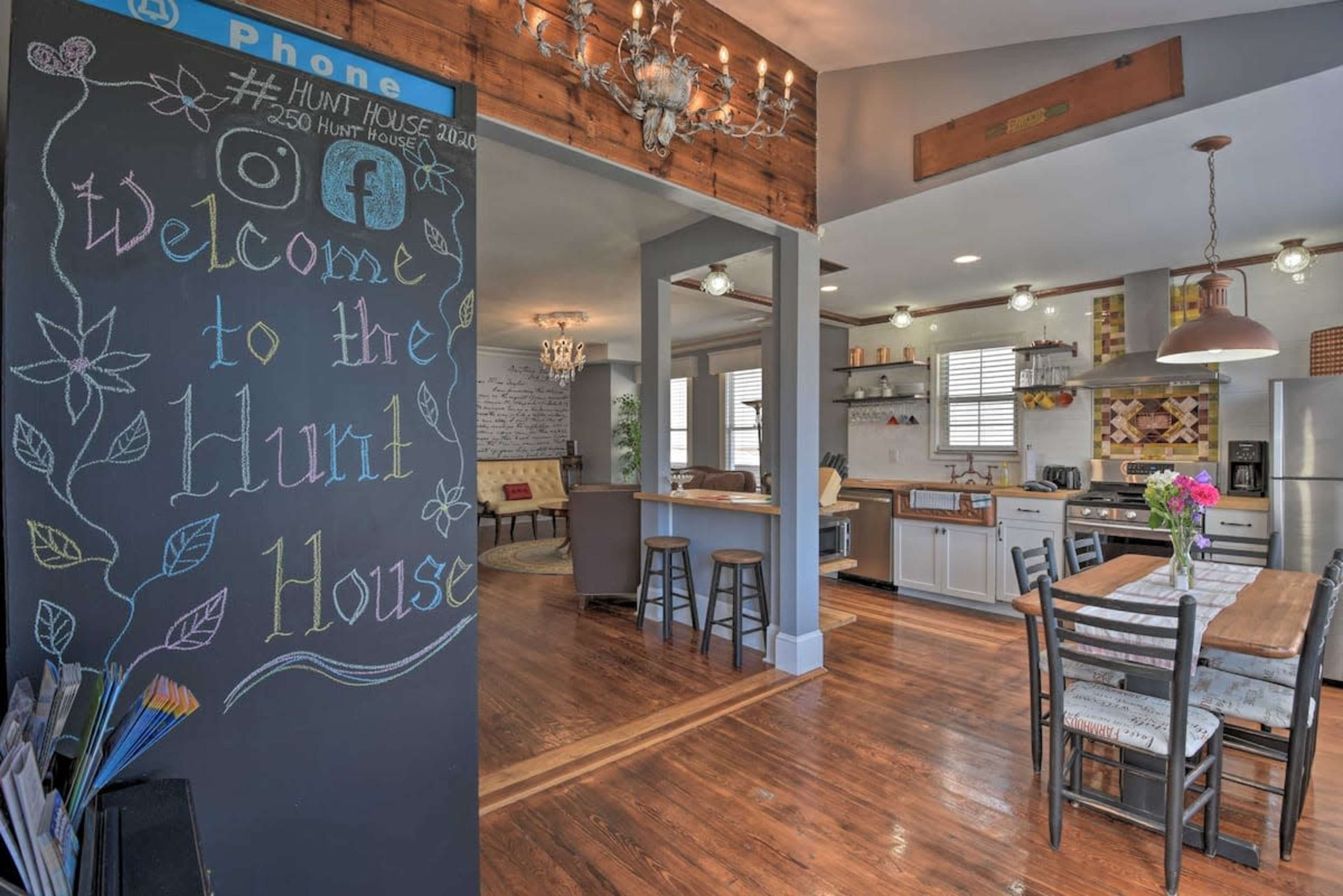 A spacious kitchen and dining area features a chalkboard welcoming guests to the "Hunt House," with wooden accents and modern appliances.