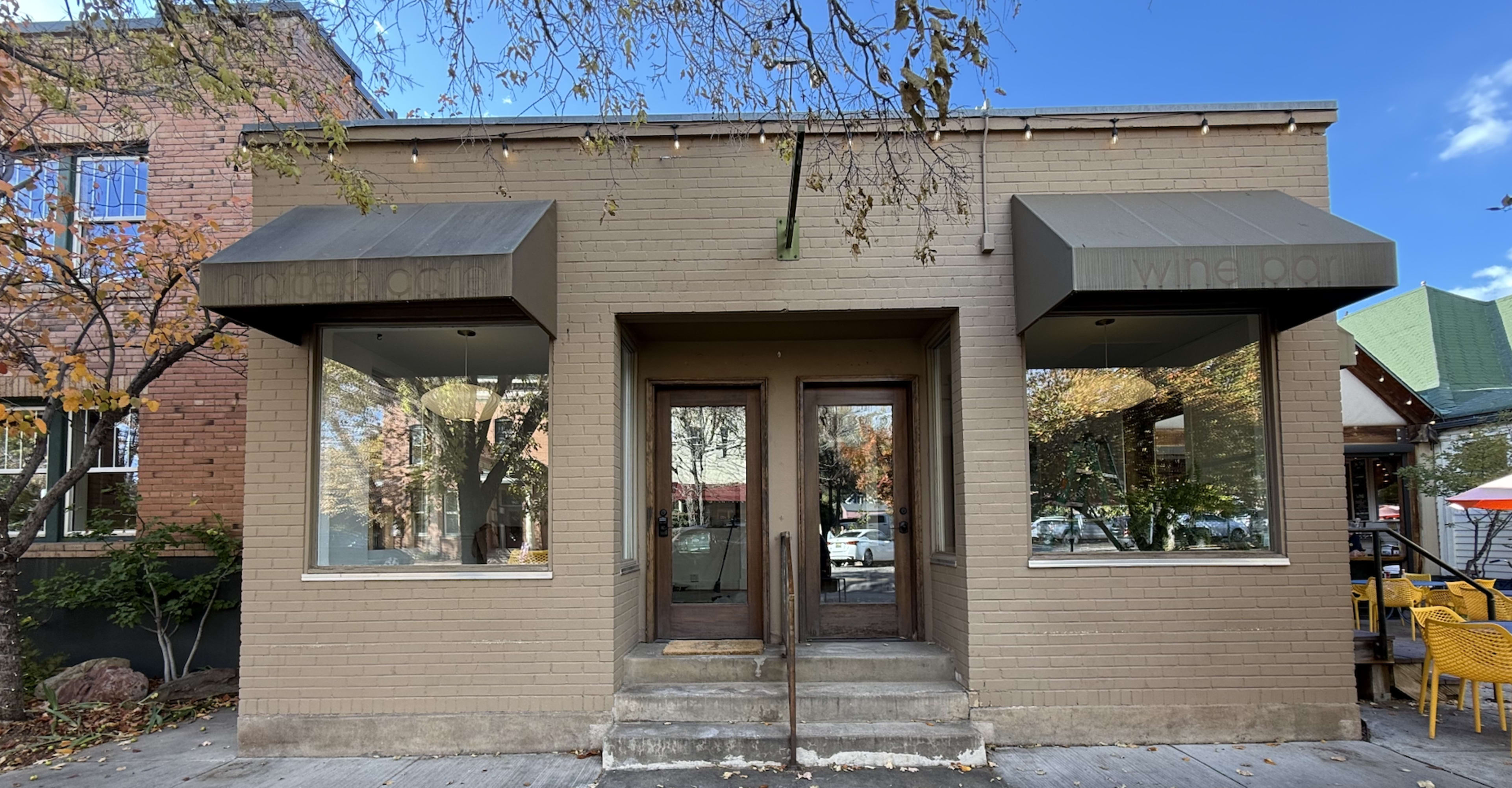 The image shows the exterior of a brick building with two large windows and a double-door entrance, flanked by awnings labeled "mother" and "wine bar."