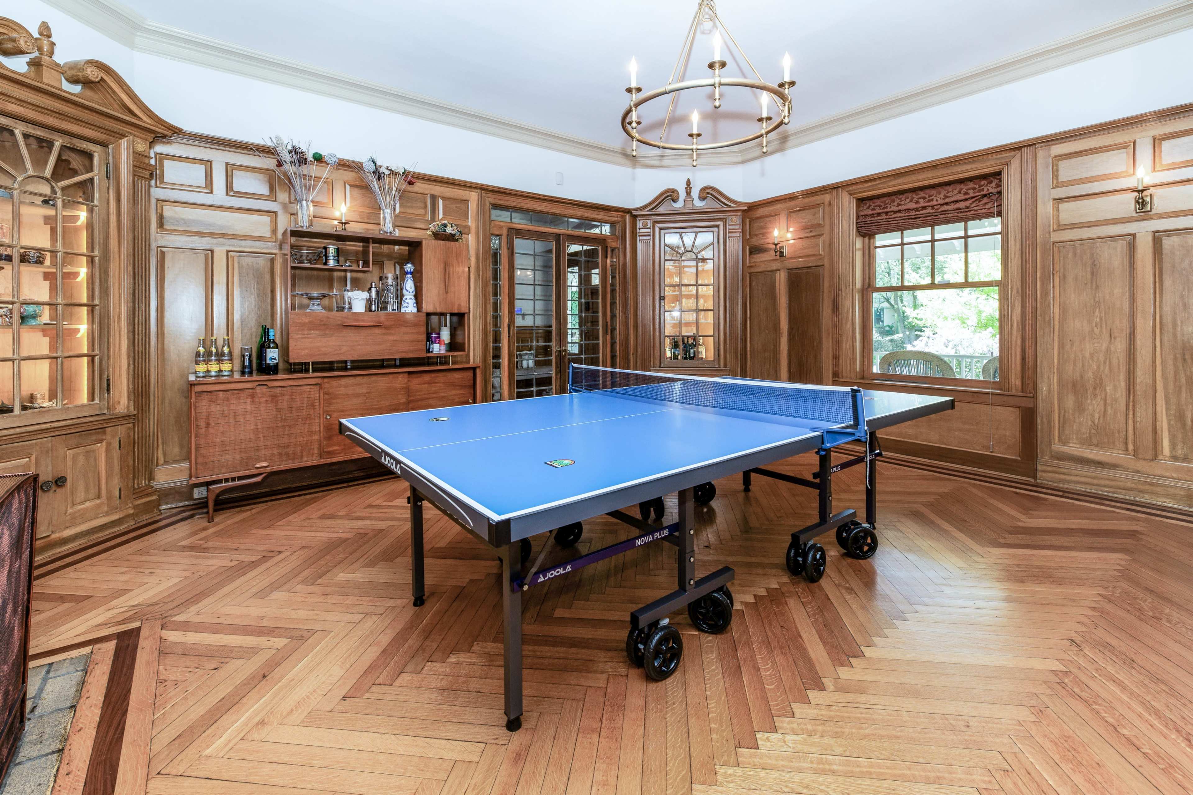 A table tennis table set up in a room with wooden paneling and built-in cabinetry.