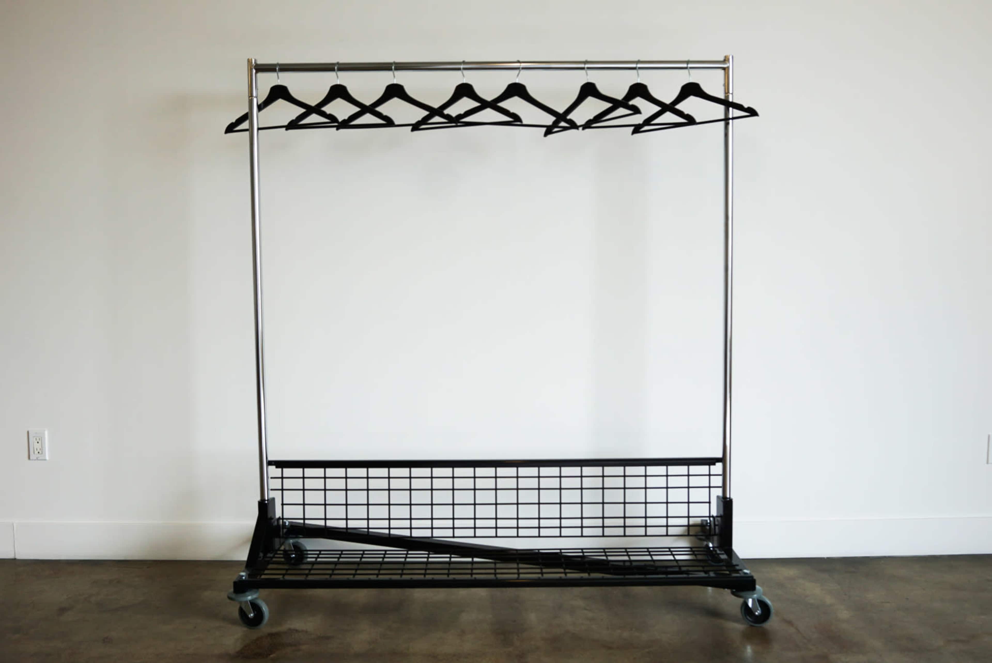 The image shows a metal clothing rack with a black wire base, featuring several empty black hangers.