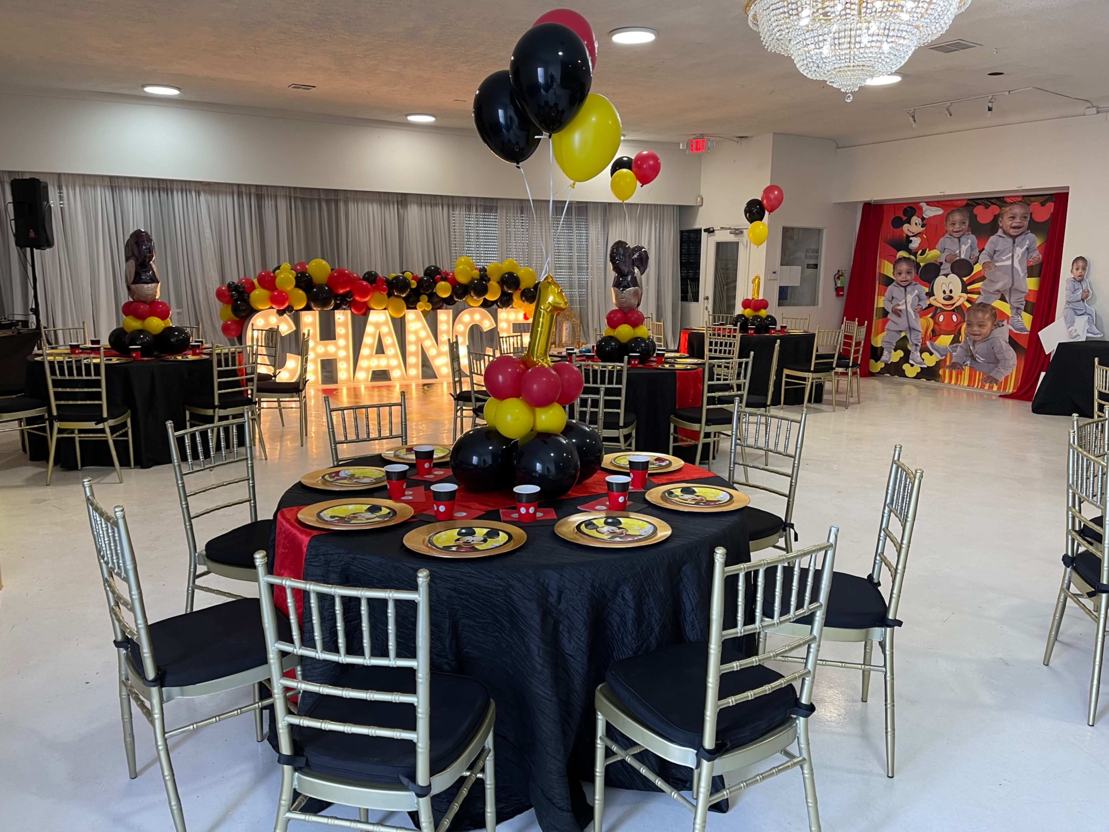 The scene features a decorated banquet hall with tables set for a celebration, adorned with black and gold tablecloths, red and black balloon arrangements, and a large illuminated sign that reads "CHANGE."