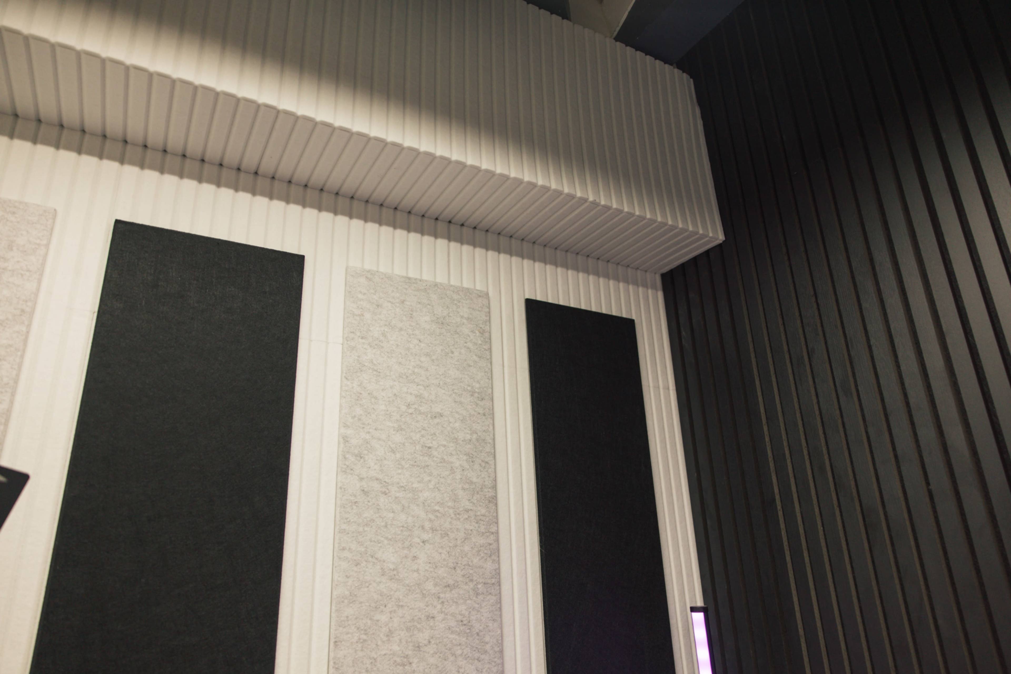 A corner of a room featuring acoustic panels with a combination of white and black textures on the walls.