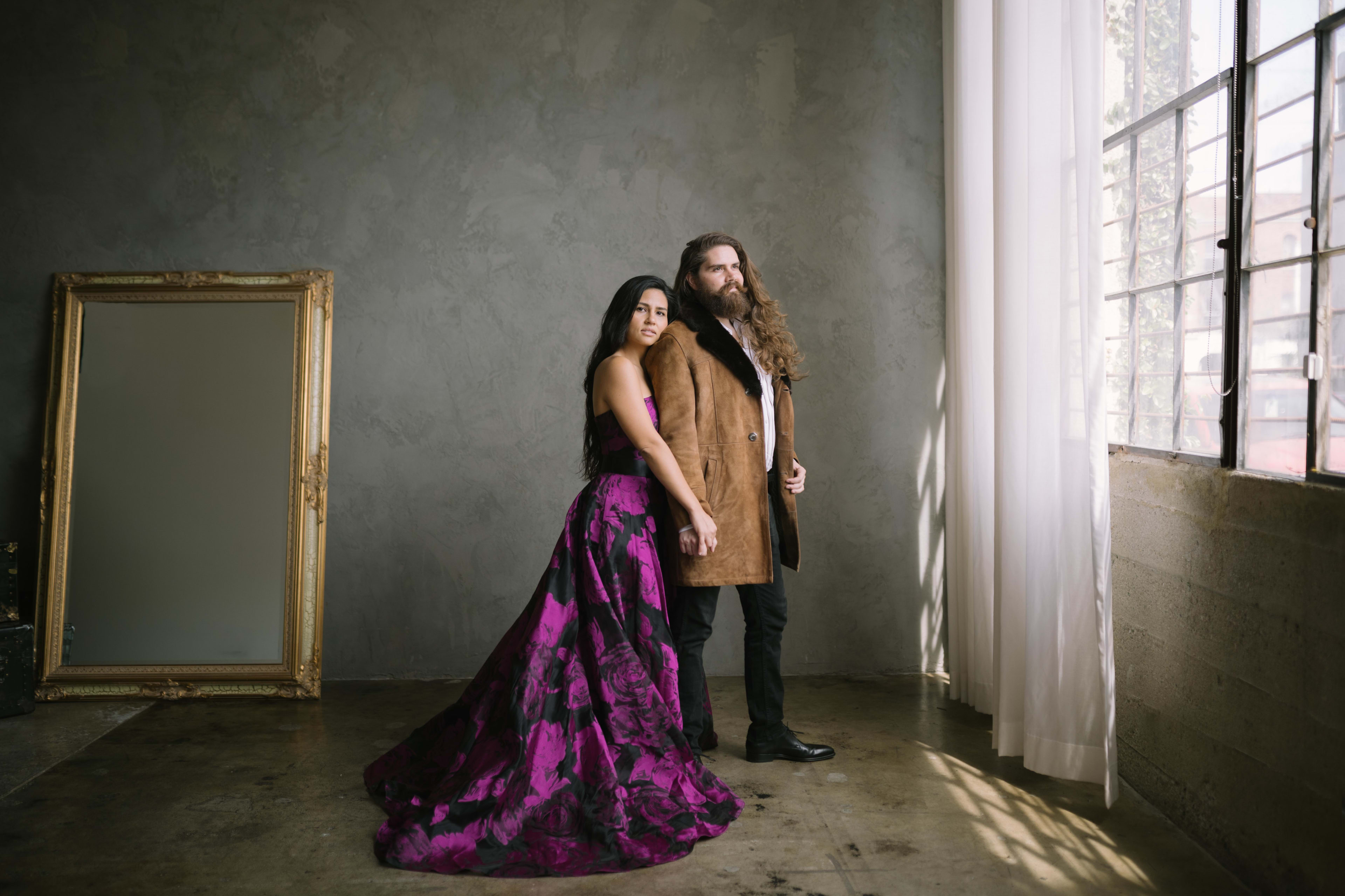 A couple posing for a photo shoot next to a mirror.