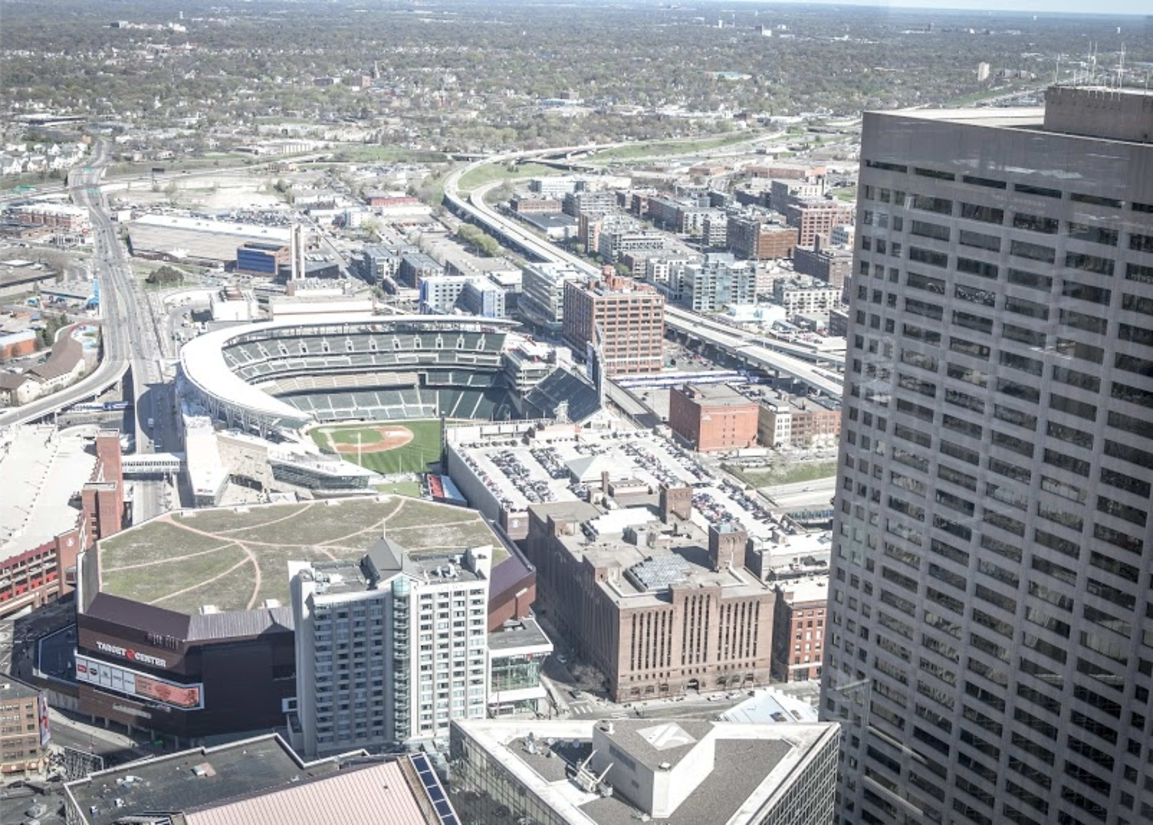 A panoramic view of a cityscape featuring a baseball stadium surrounded by various buildings and roads.