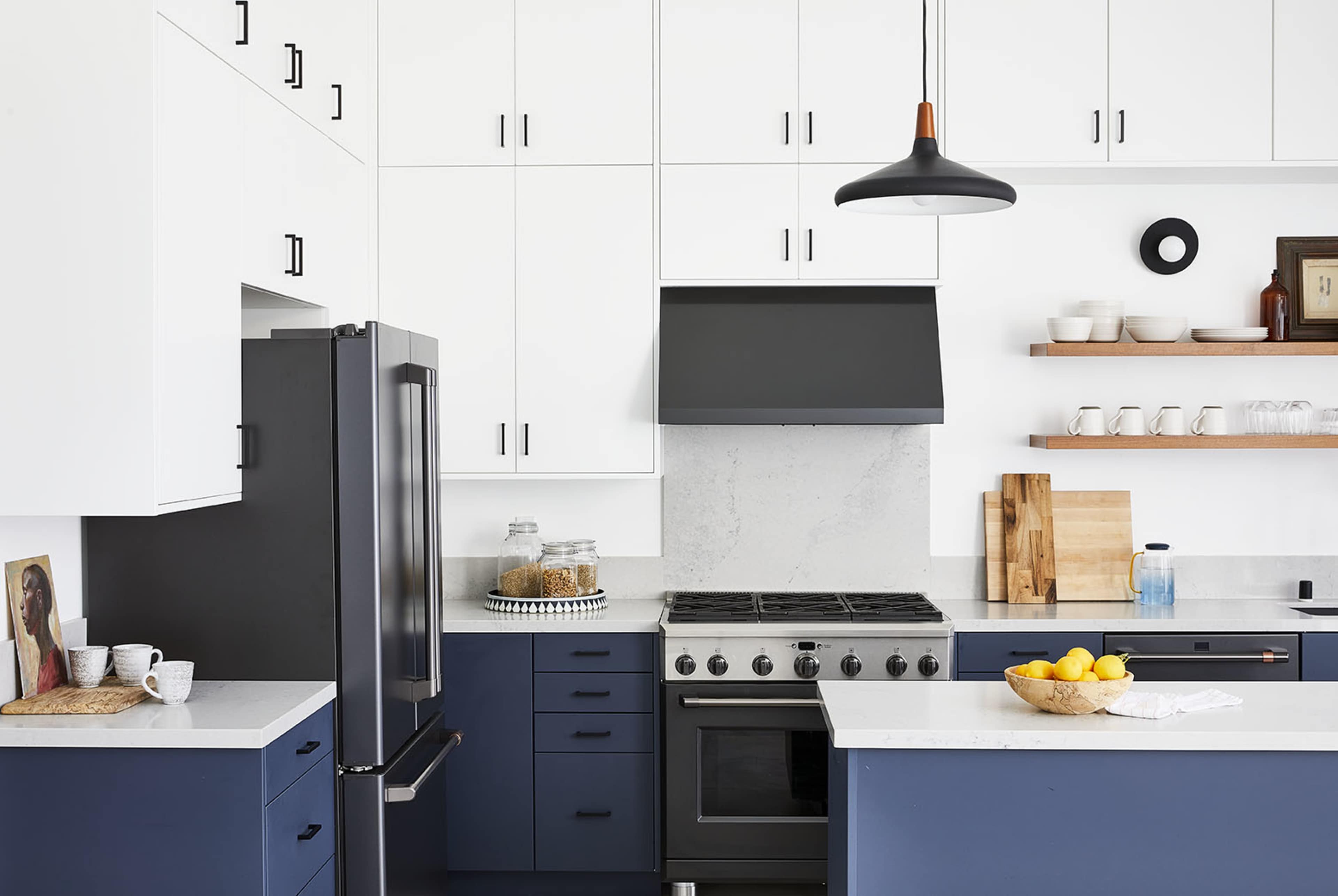 The kitchen features navy blue cabinetry, a black refrigerator, a stainless steel oven, and a marble countertop with a bowl of lemons.