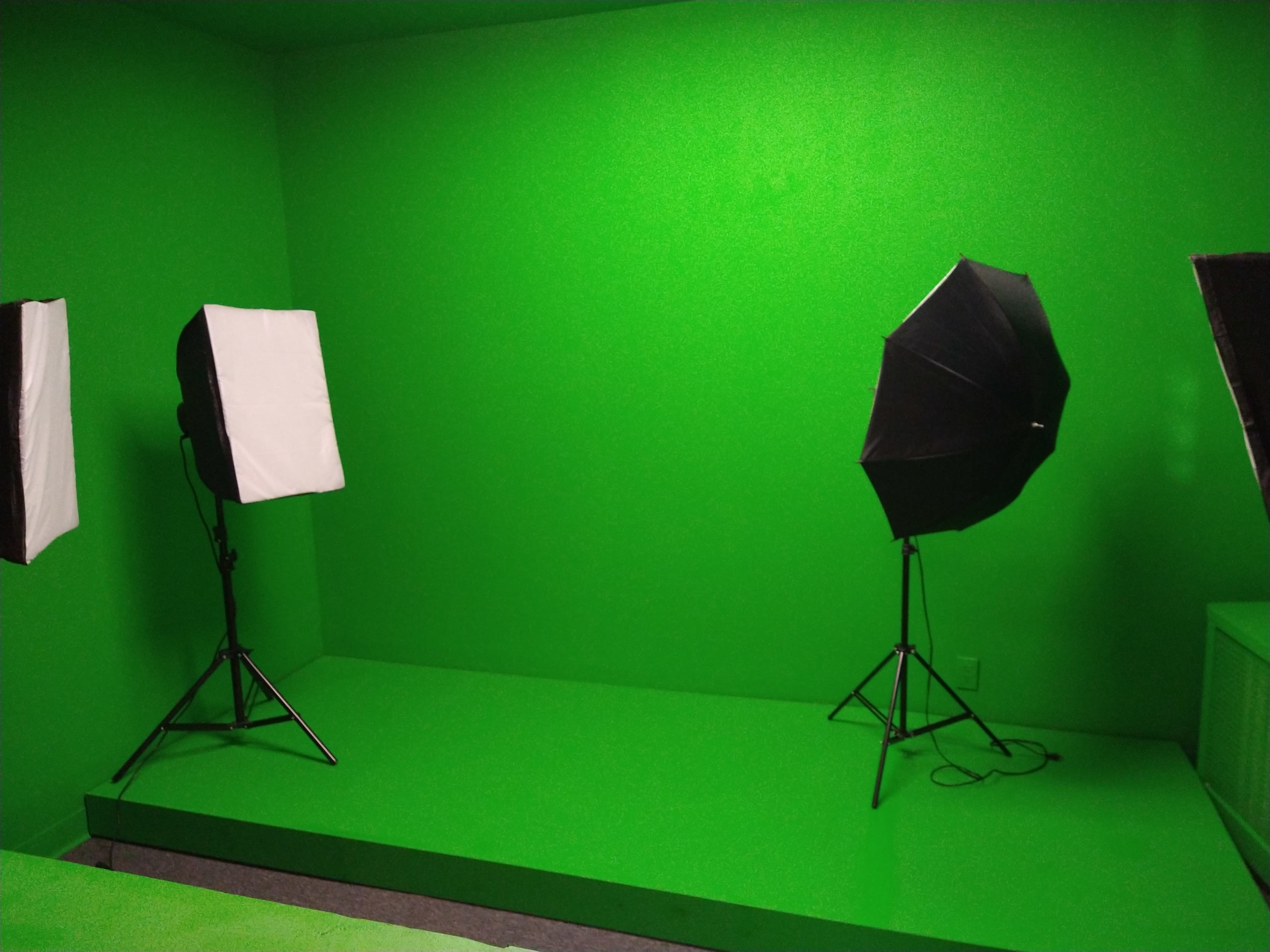 The image shows a studio space with three lighting setups against a bright green backdrop.