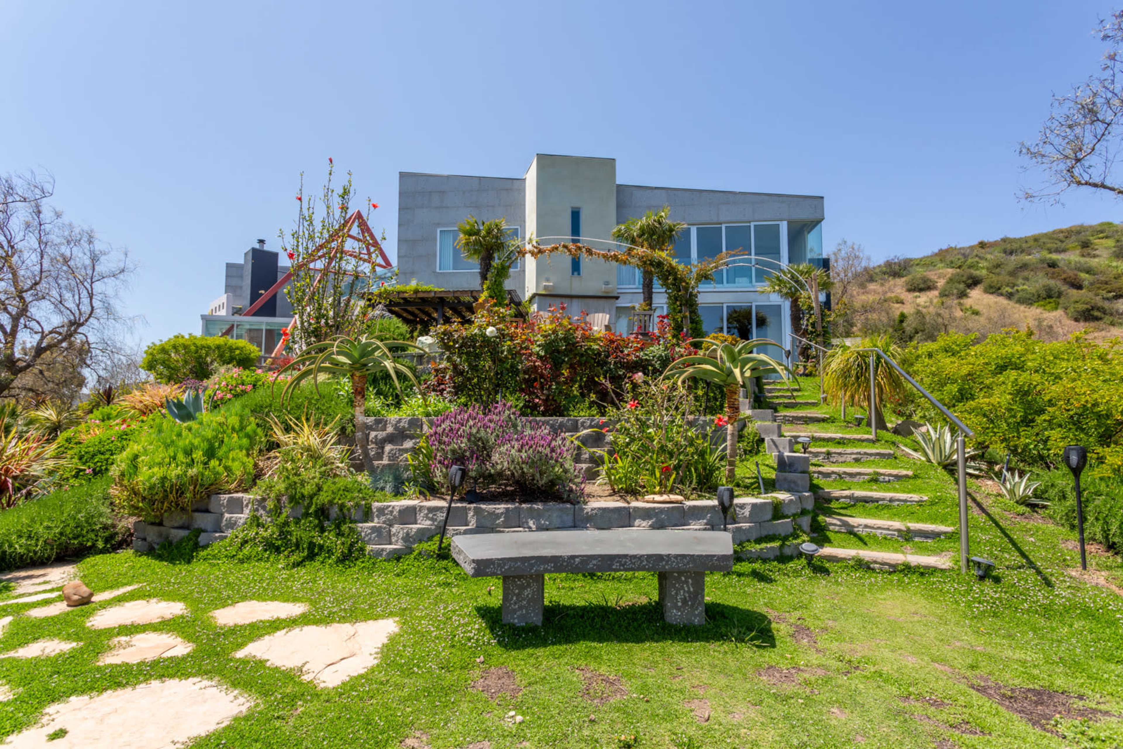 A modern house surrounded by a landscaped garden with steps leading up to the entrance.