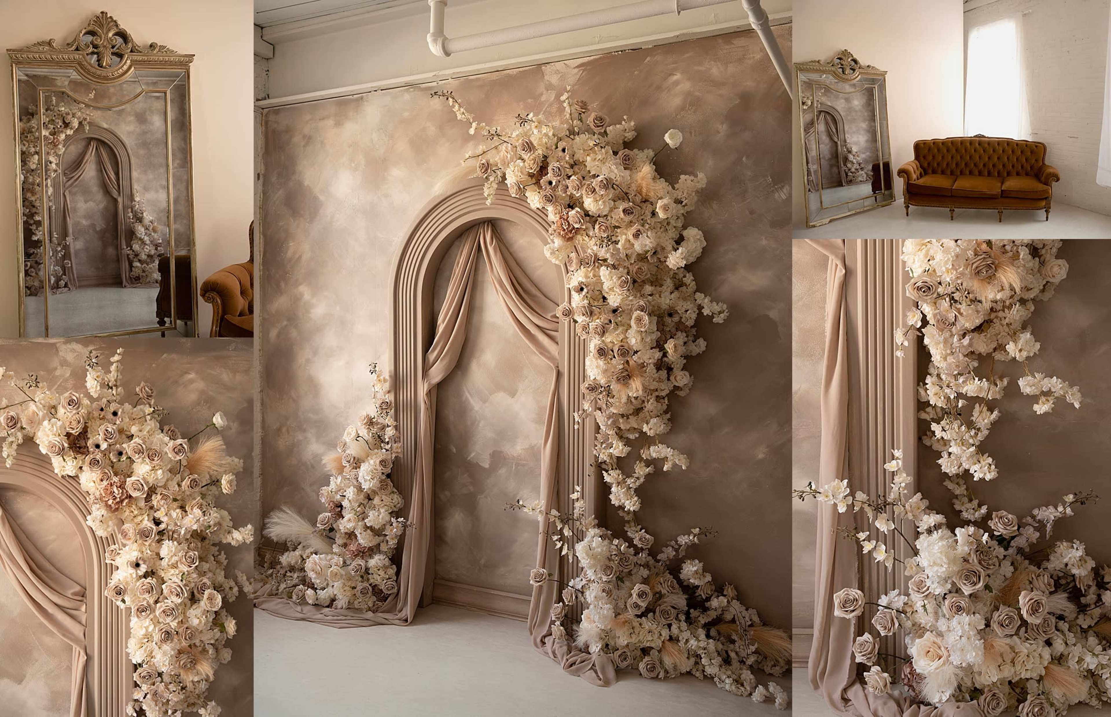 The image showcases a decorated interior featuring a large floral arrangement cascading from a fabric draped arch, complemented by a vintage mirror and a brown couch against a softly textured wall.