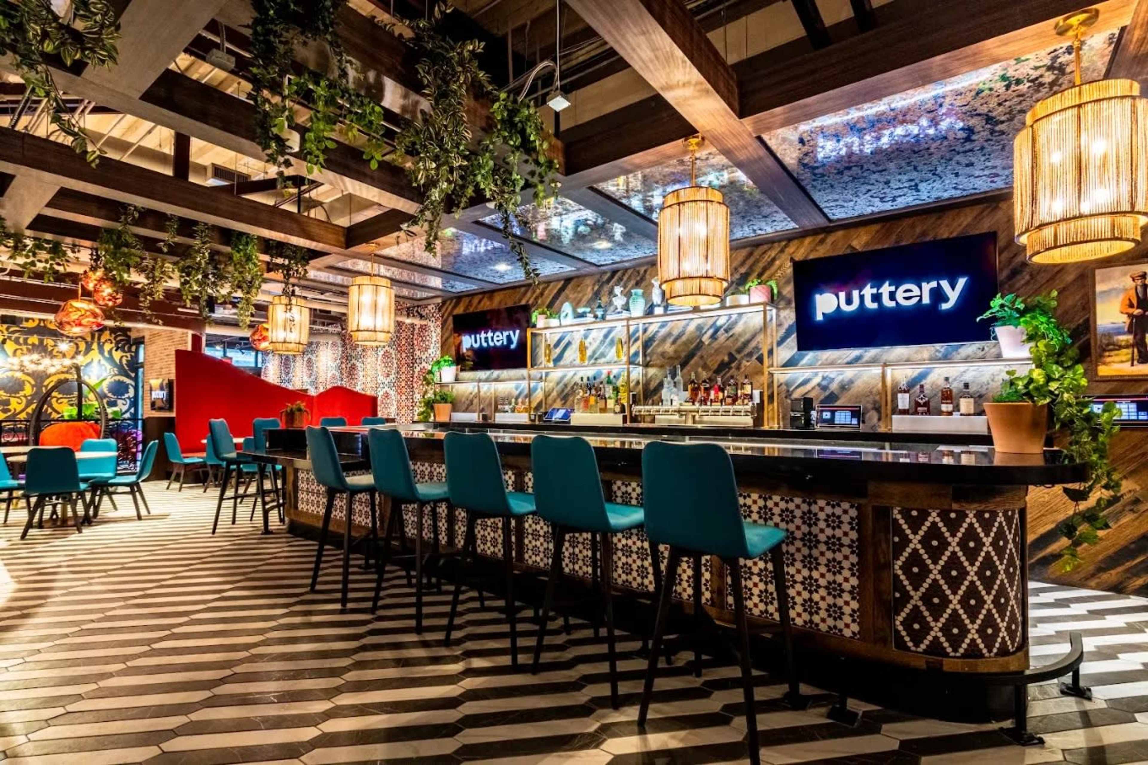 The image shows a bar area with high stools, a colorful tiled floor, and decorative hanging lights.