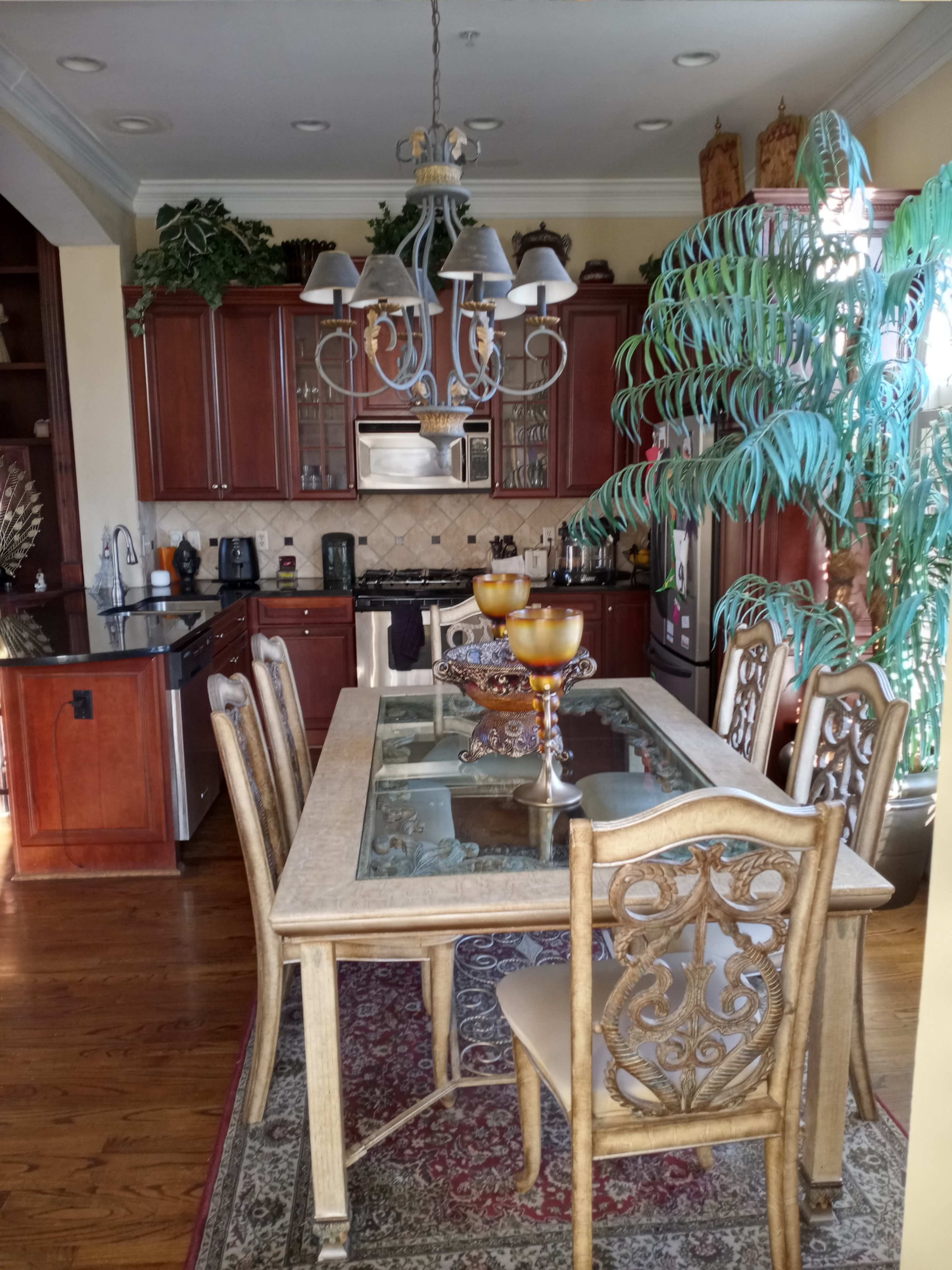 A kitchen with wooden cabinets, a dining table set with decorative items, and a large indoor plant.