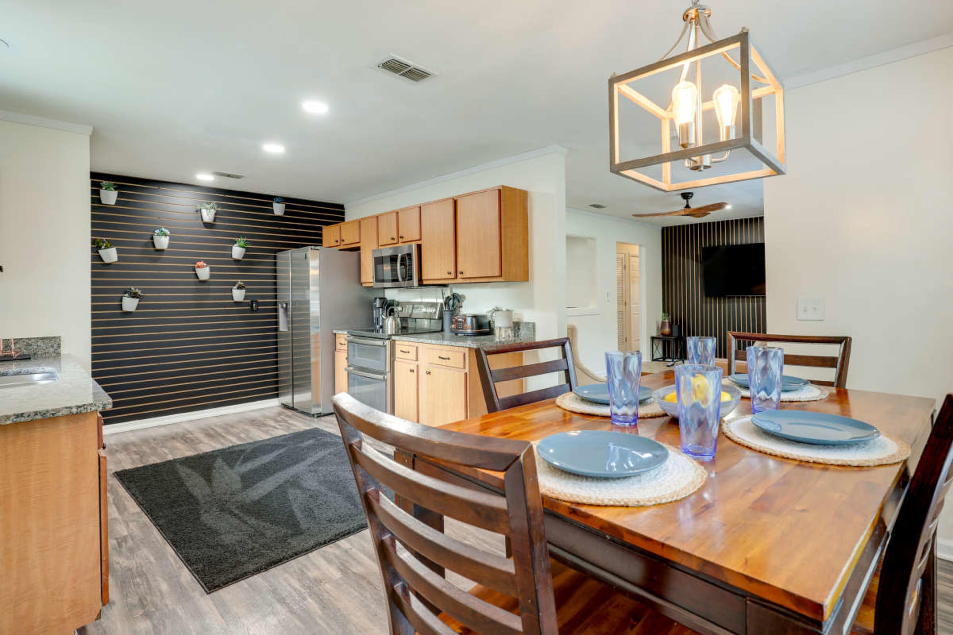 A kitchen with wooden cabinets, a dining table set for four, and stainless steel appliances.