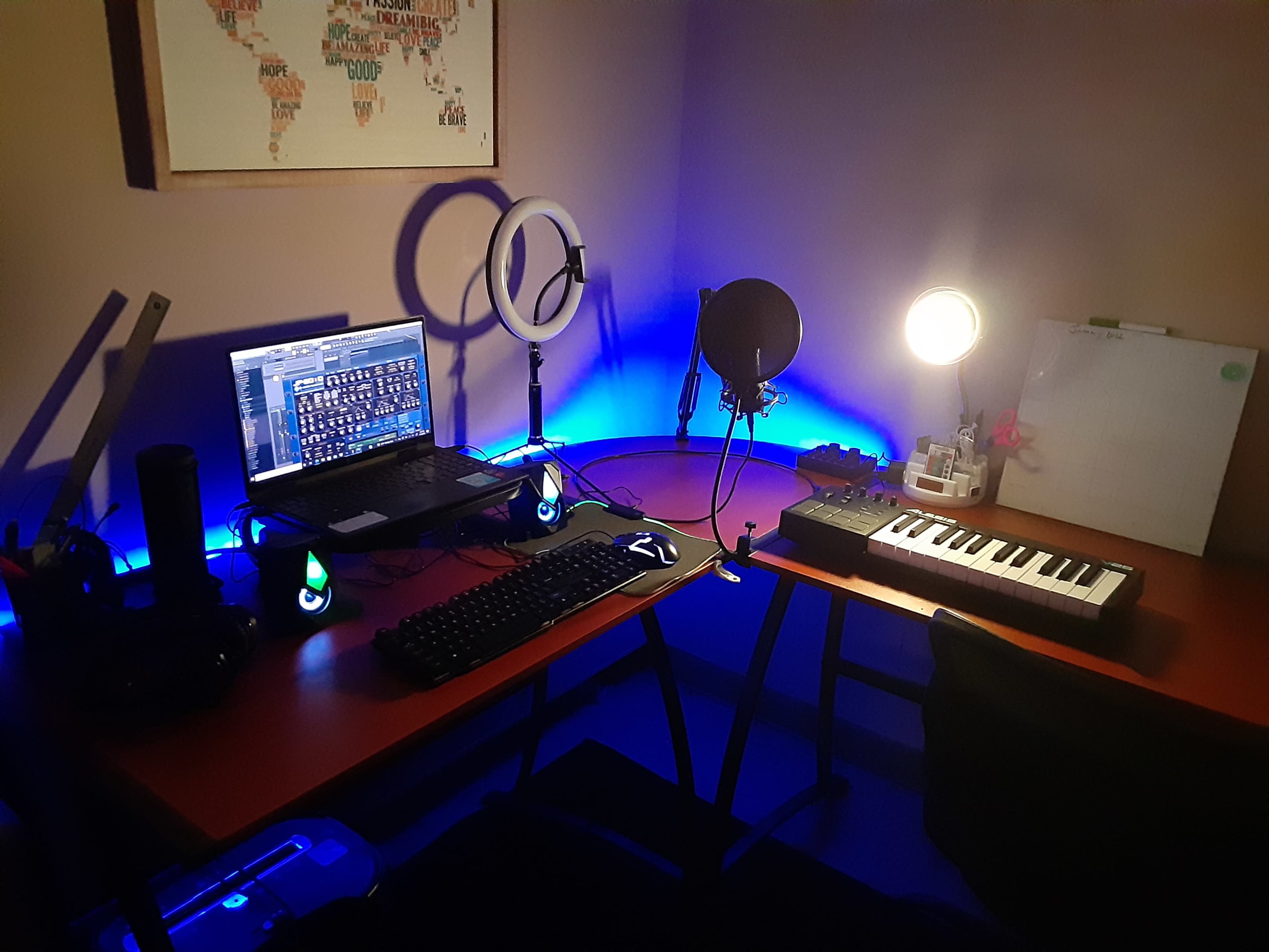 A workspace is set up with a laptop, keyboard, microphone, and decorative lighting.