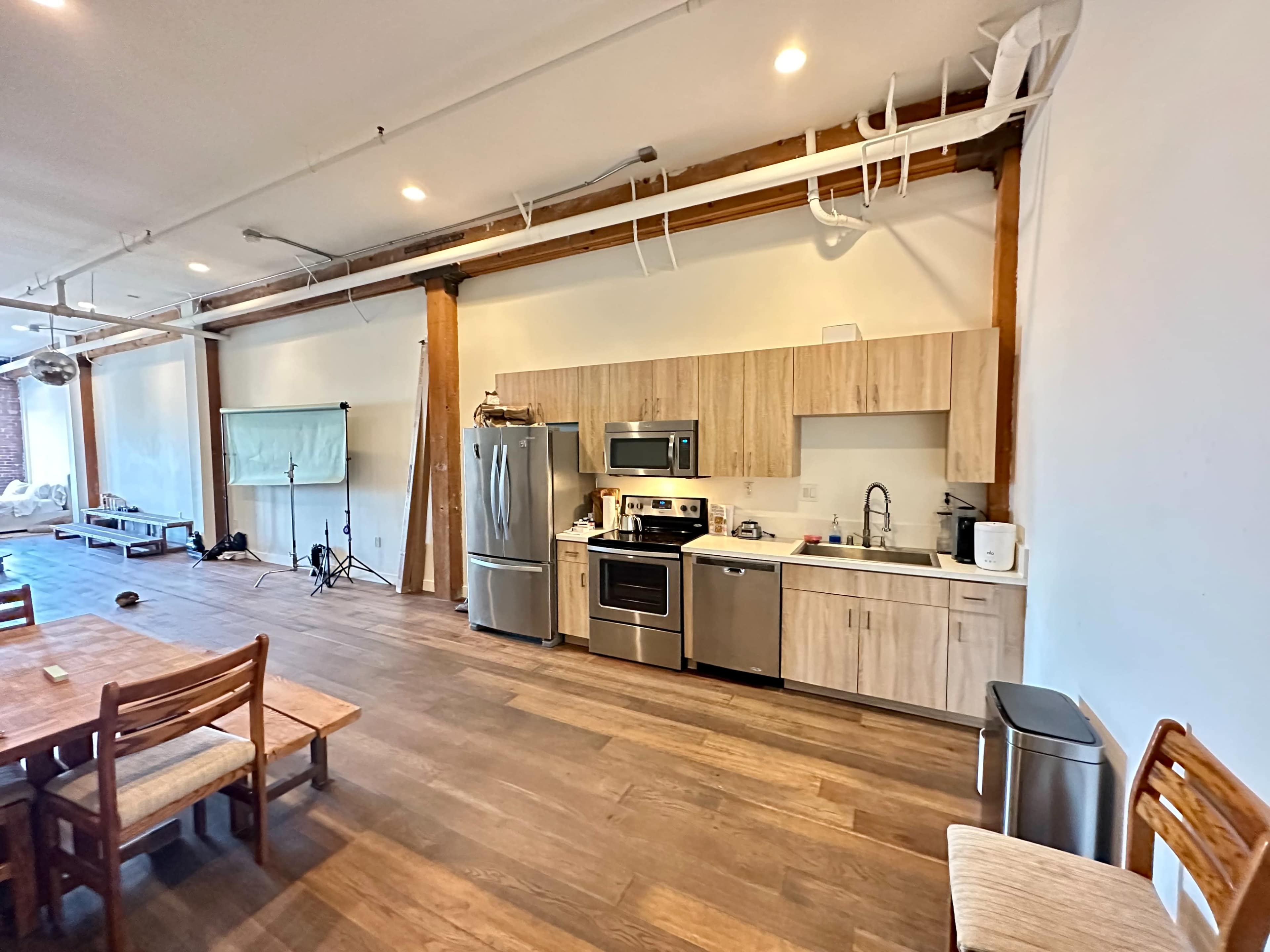 The image shows a modern kitchen with stainless steel appliances and wooden cabinetry in a spacious room with hardwood flooring.