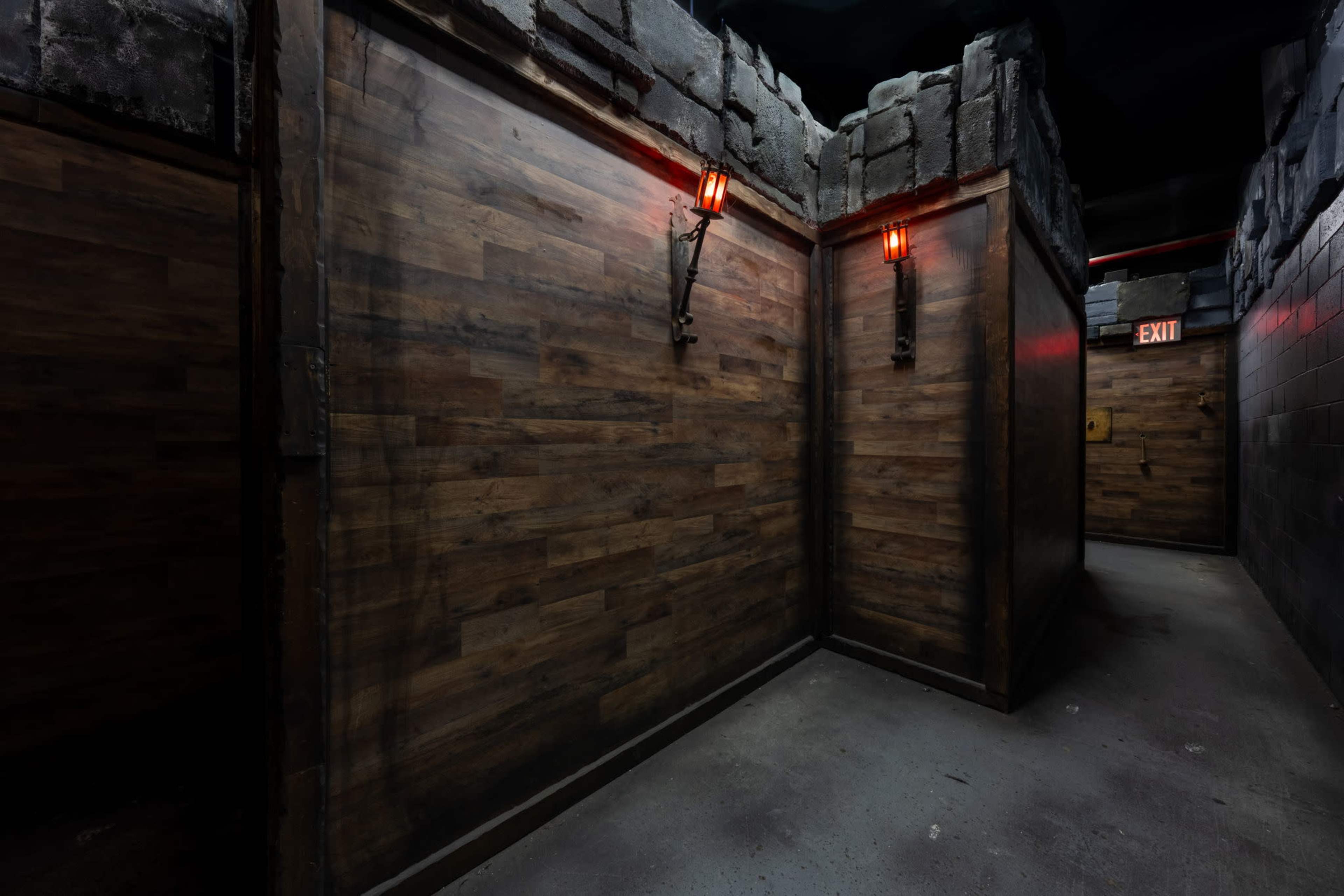 The image features a dimly lit corridor with wooden walls, stone accents, and two glowing red wall sconces.