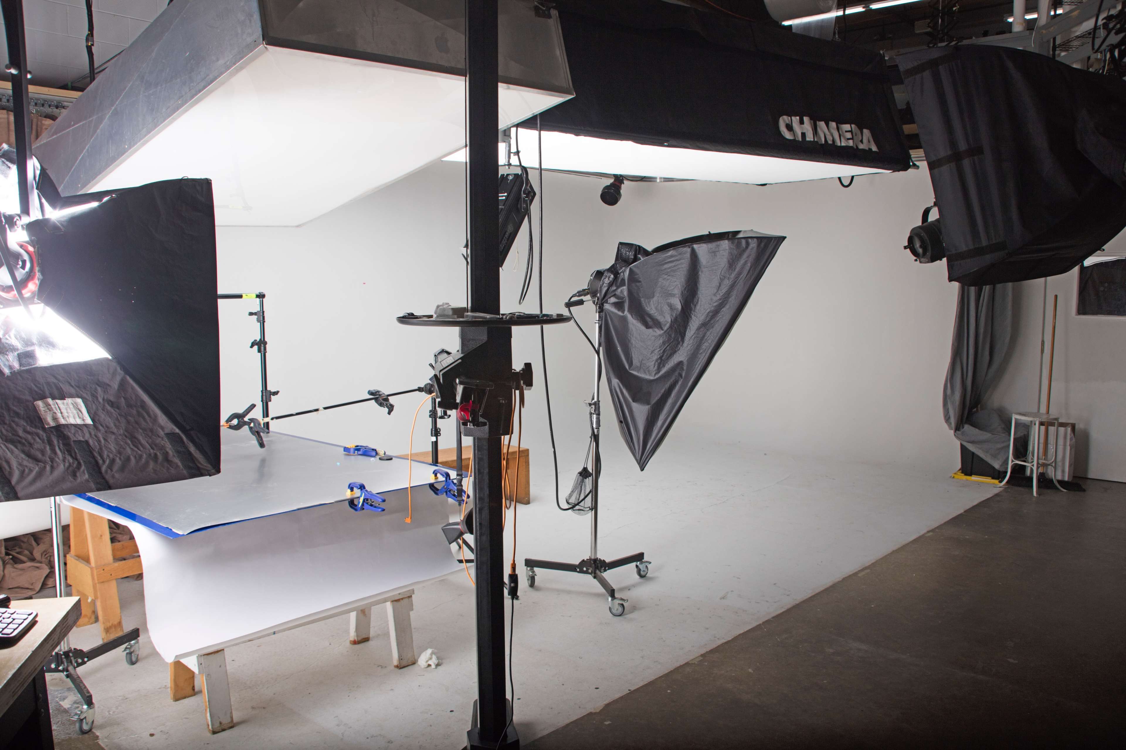 A photography studio equipped with softboxes, a backdrop, and a table set up for a shoot.