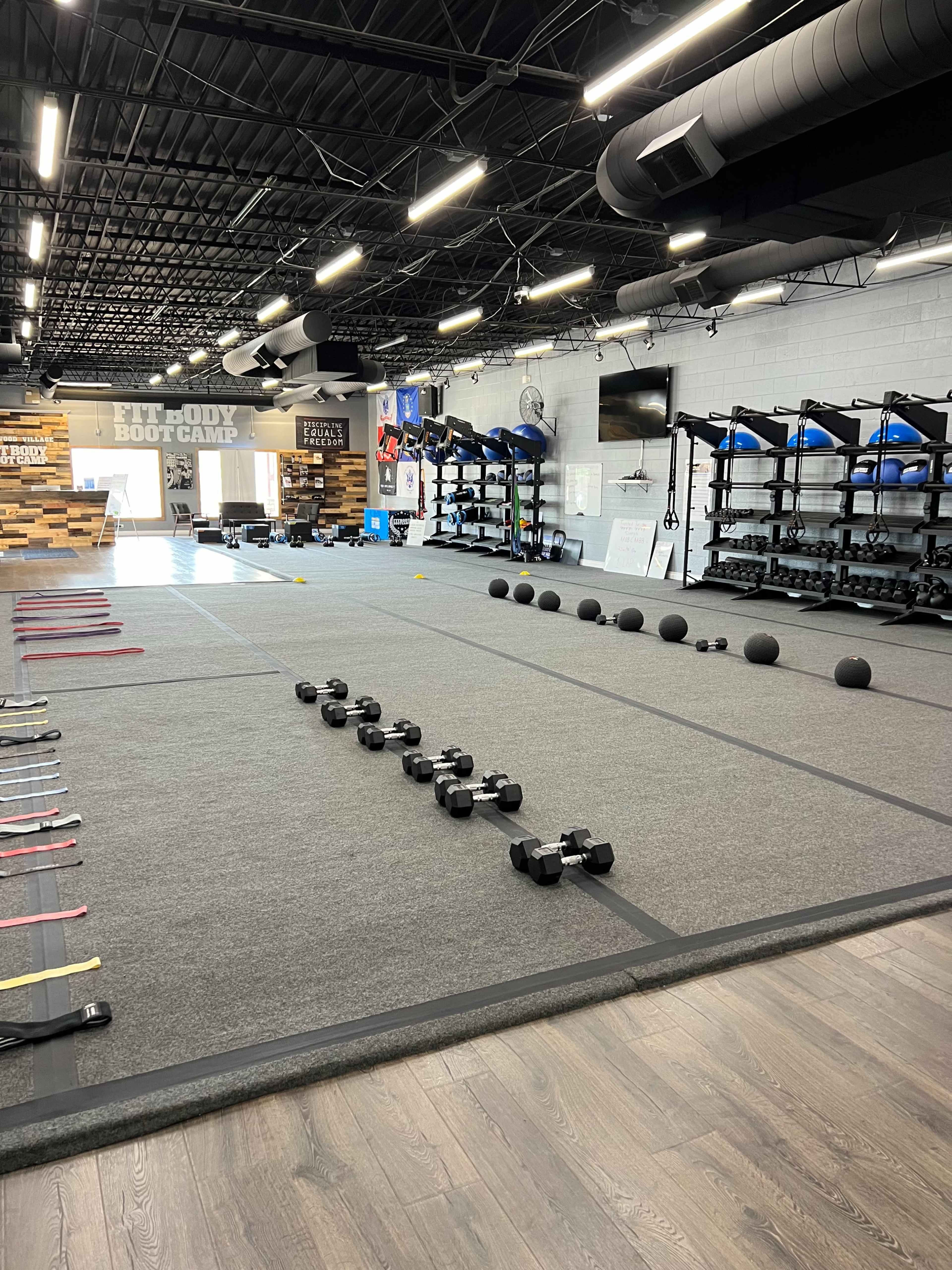 A fitness facility with workout equipment including dumbbells, medicine balls, resistance bands, and designated exercise areas.