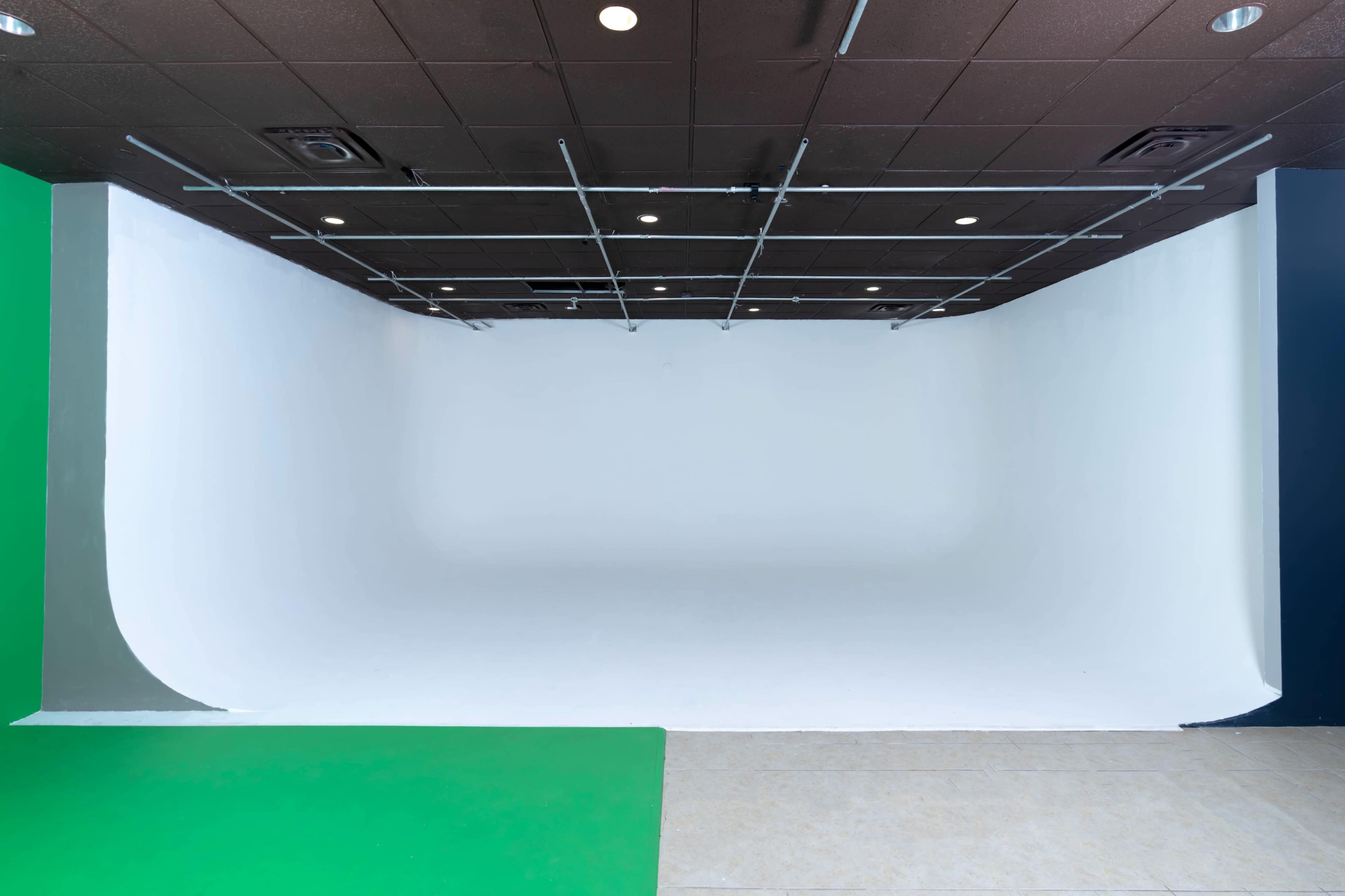 A spacious photography studio with a seamless white backdrop and a green section on the floor.