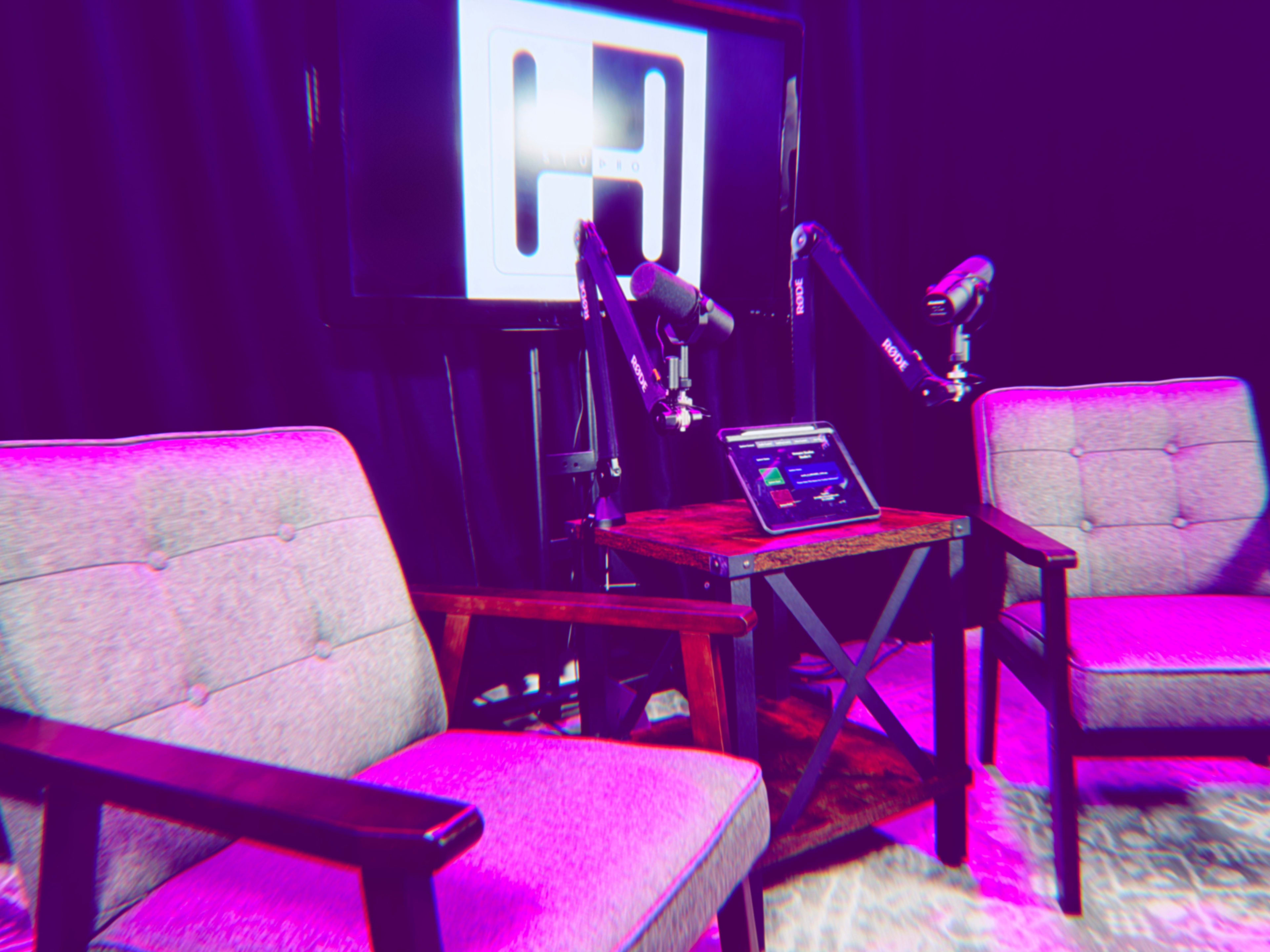 The image features a podcasting setup with two empty chairs, a wooden table, and microphones, all in front of a digital screen displaying a logo.