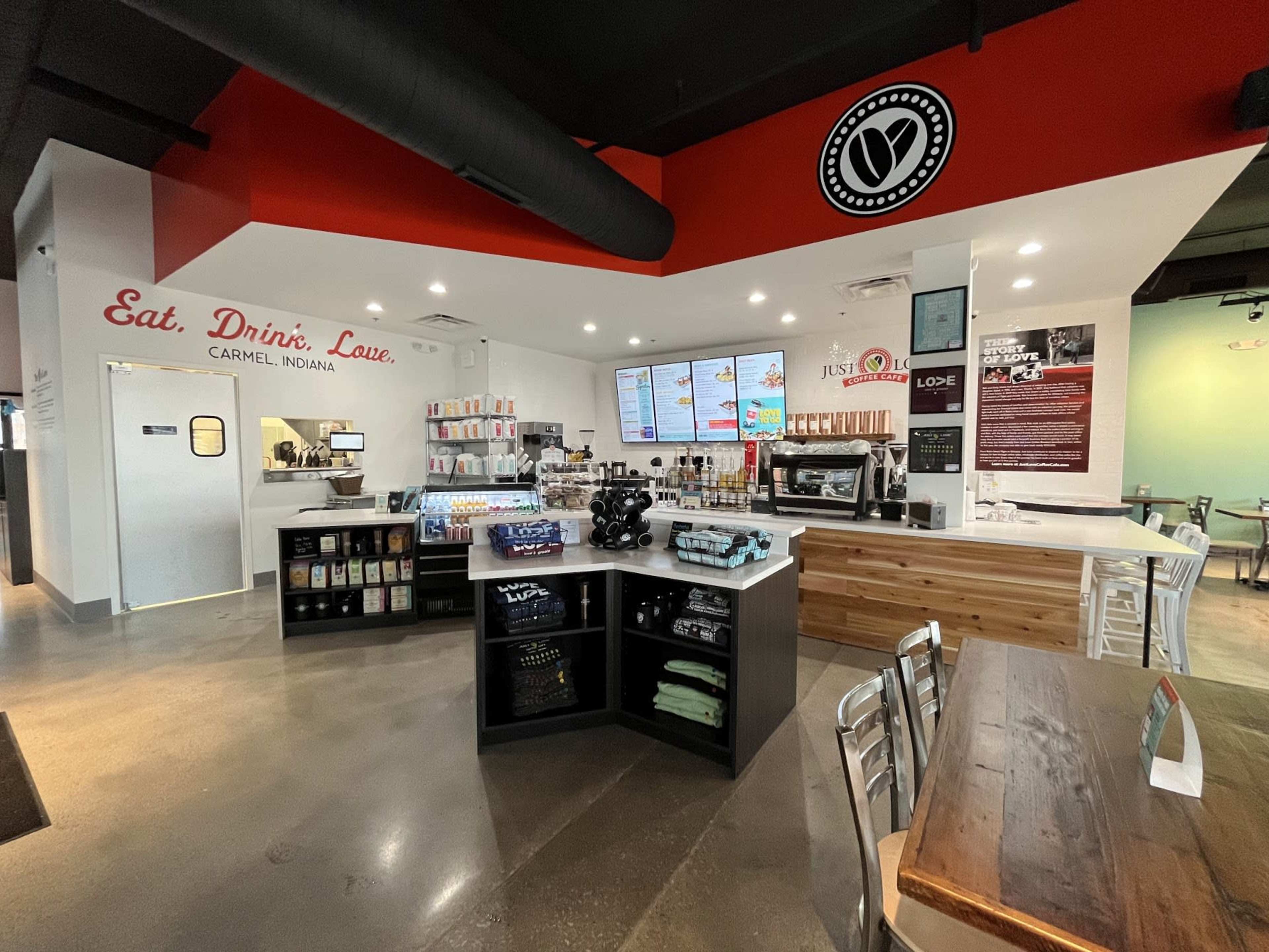 A modern cafe interior with a counter displaying menus, coffee equipment, and seating areas in a brightly lit space.