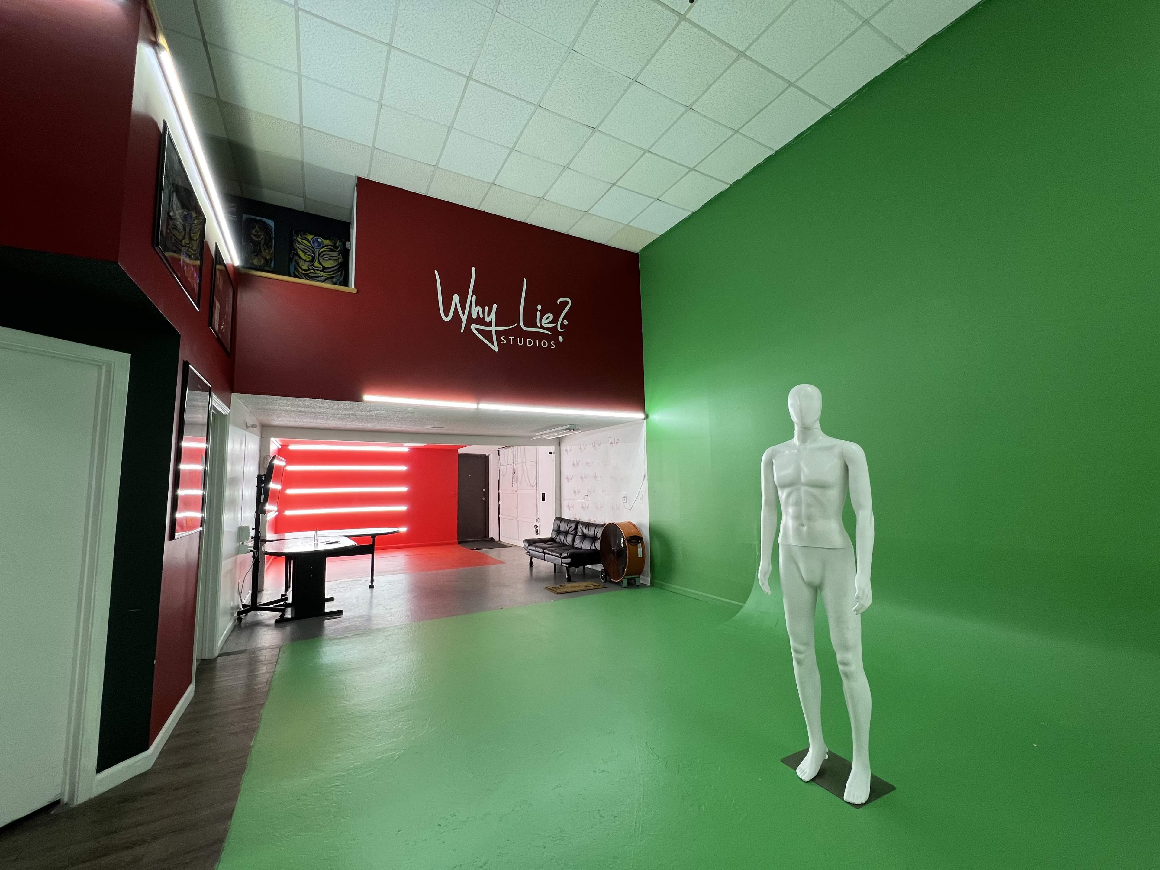 The interior of a studio features a green wall, a white mannequin, and a red accent wall with the text "Why Lie? Studio" displayed prominently.