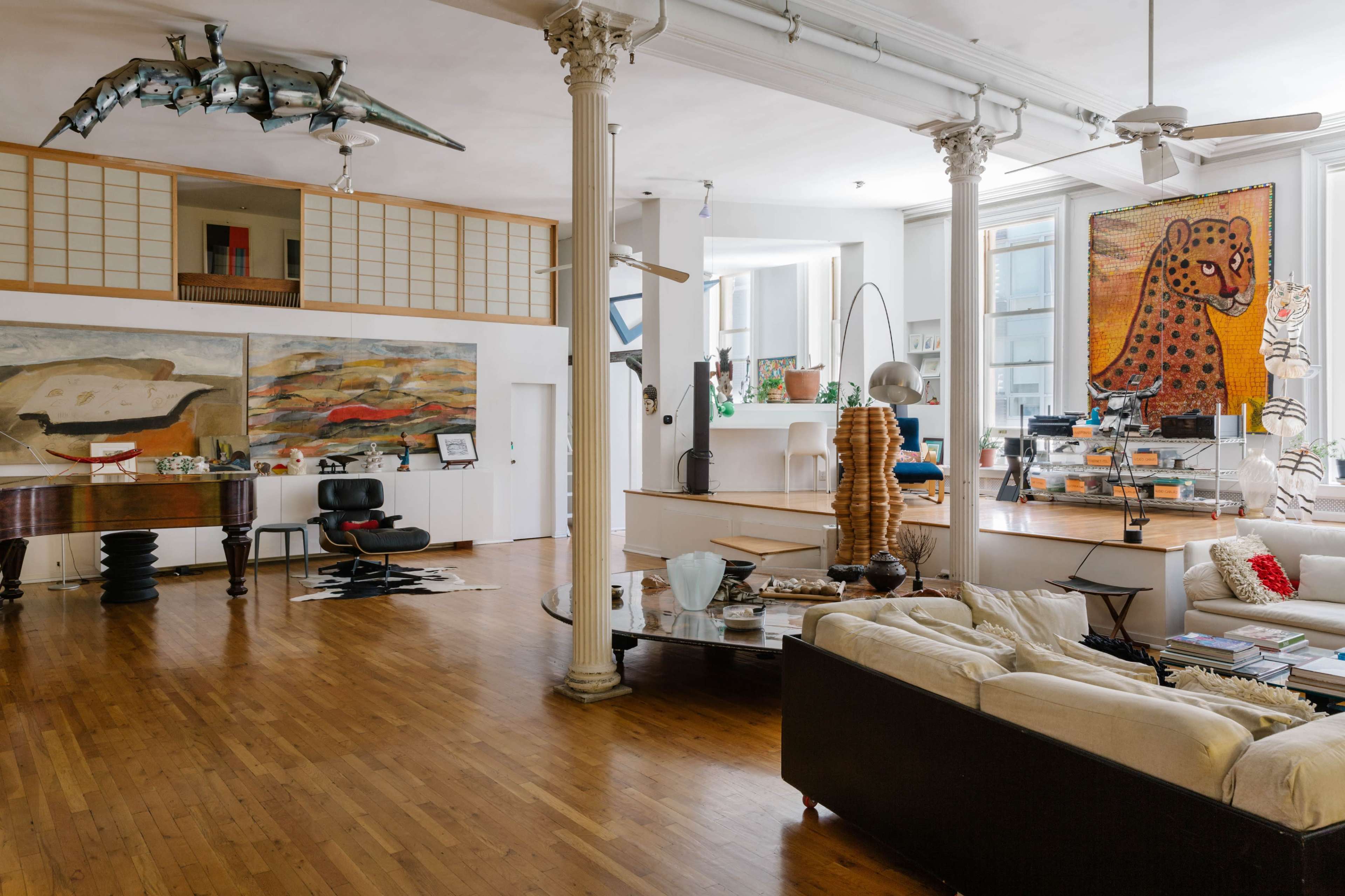 A spacious, well-lit loft featuring a piano, modern furniture, and large artworks on the walls.