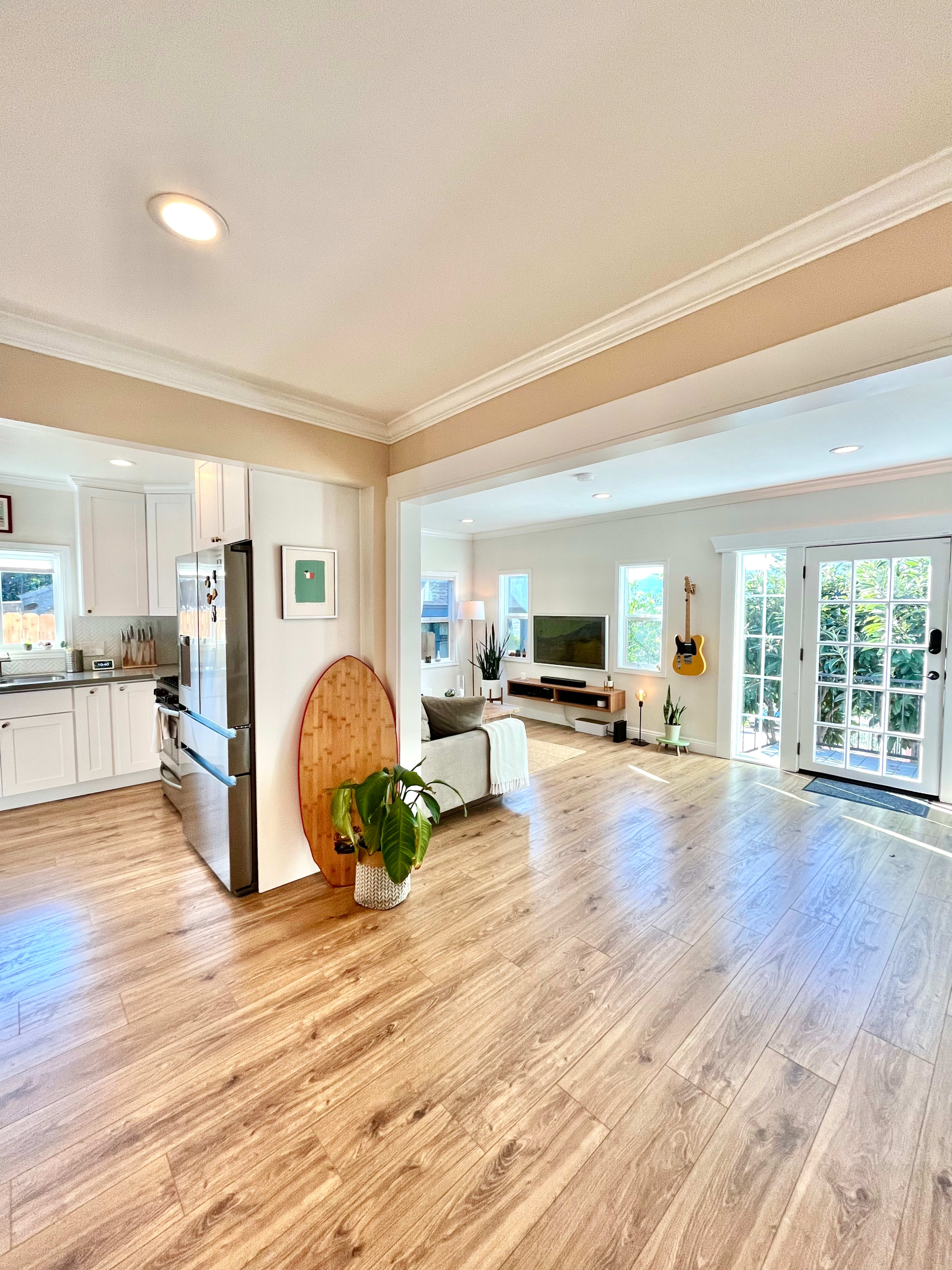 A spacious living area features a kitchen on the left, a seating area with a television on the right, and large glass doors leading outside.