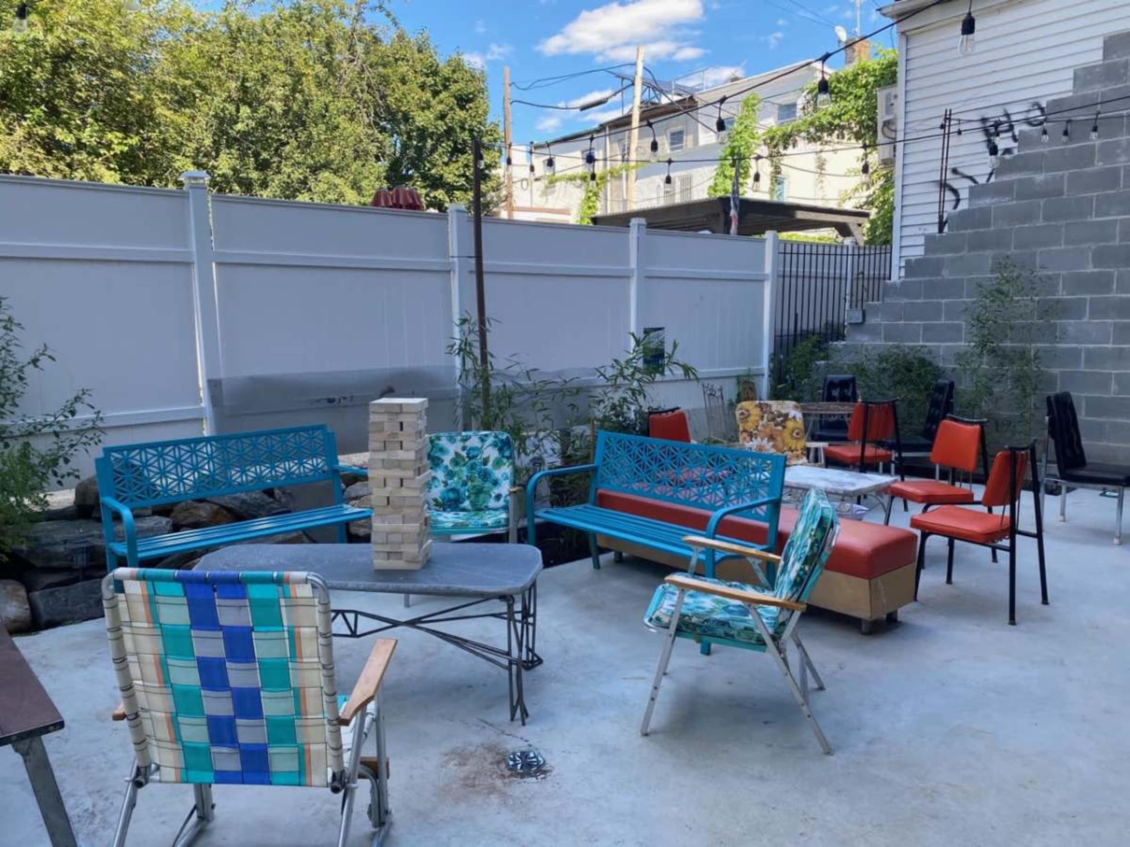 The image shows a fenced outdoor seating area with various chairs and a Jenga game set up on a table.